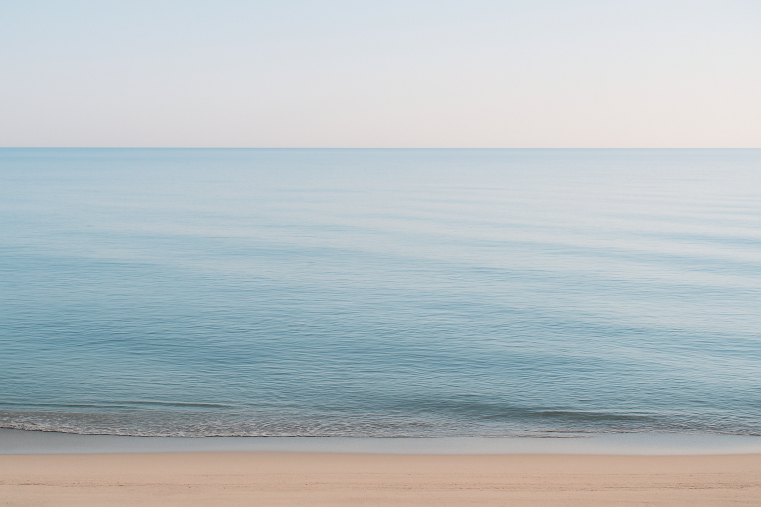 wide shot of a calm sea with empty shoreline, evoking longing and absence.