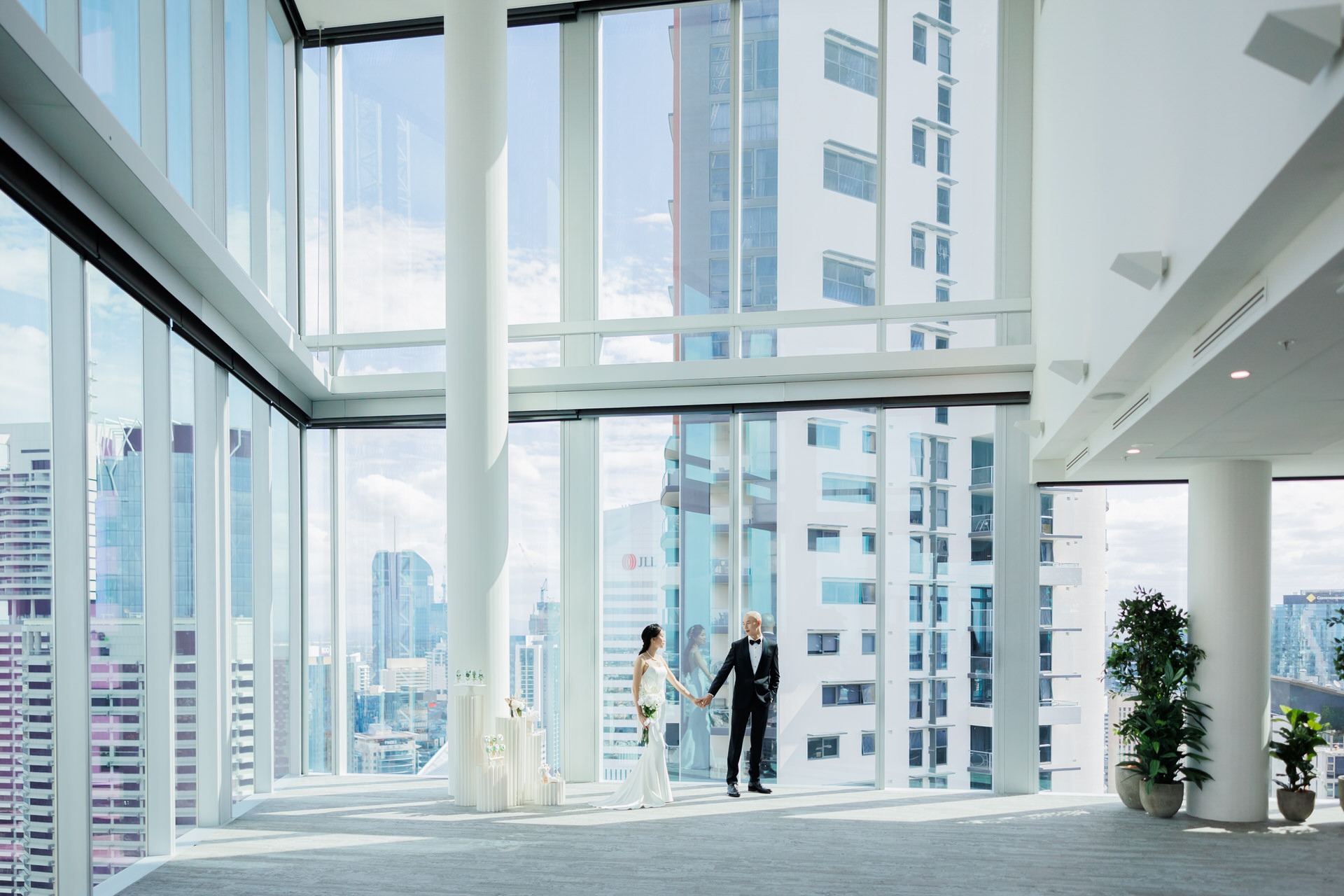 a bride and groom standing in a large room with a view of the city