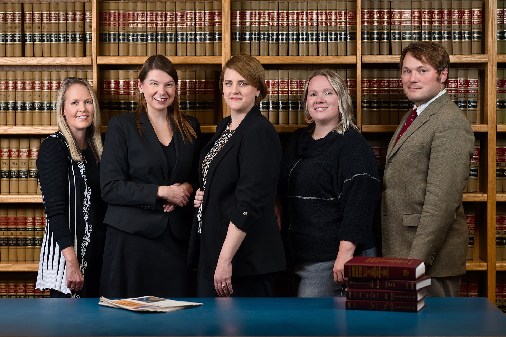 a group of people standing in front of a bookcase in a library