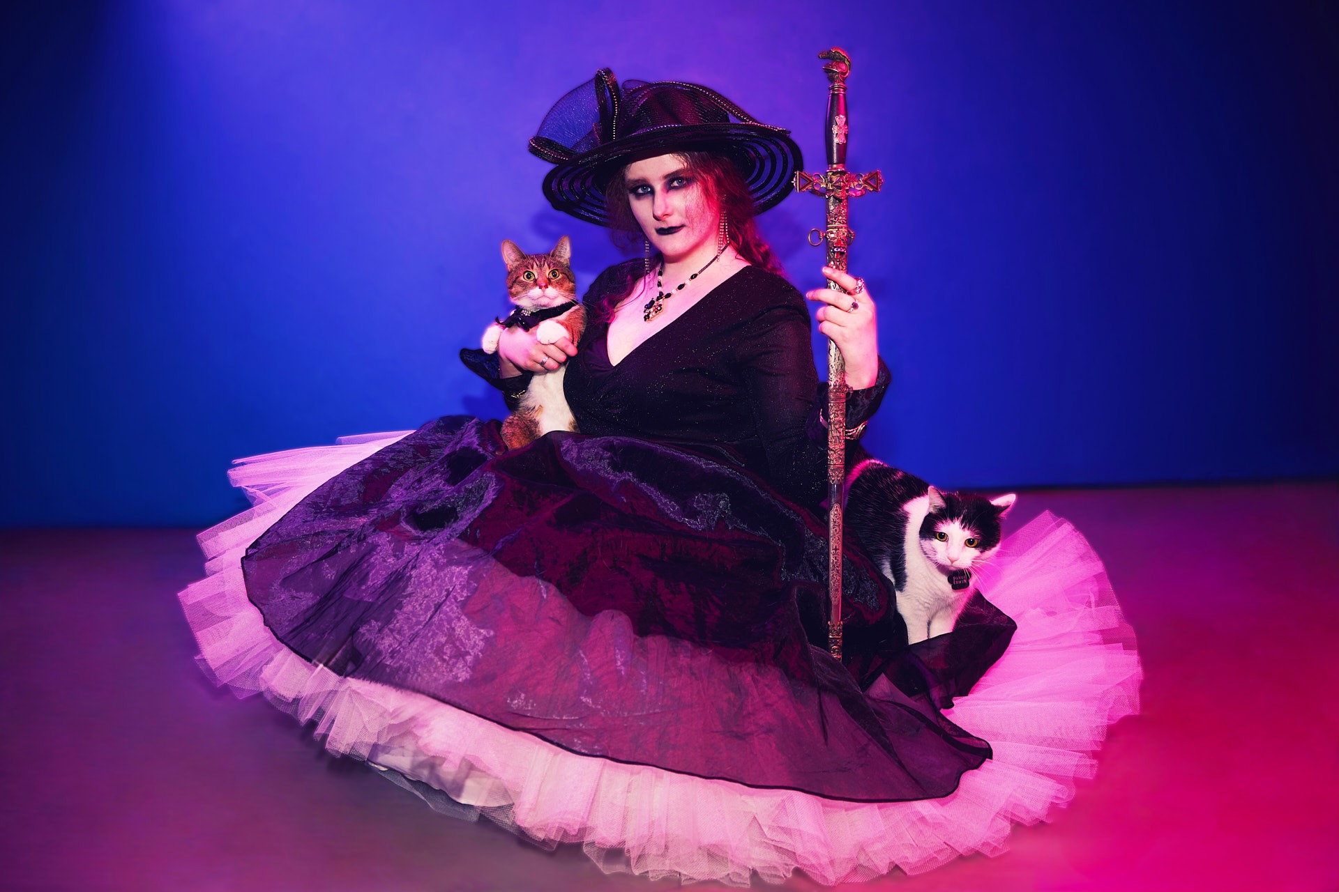 a woman in a witch costume holding a cat and a sword