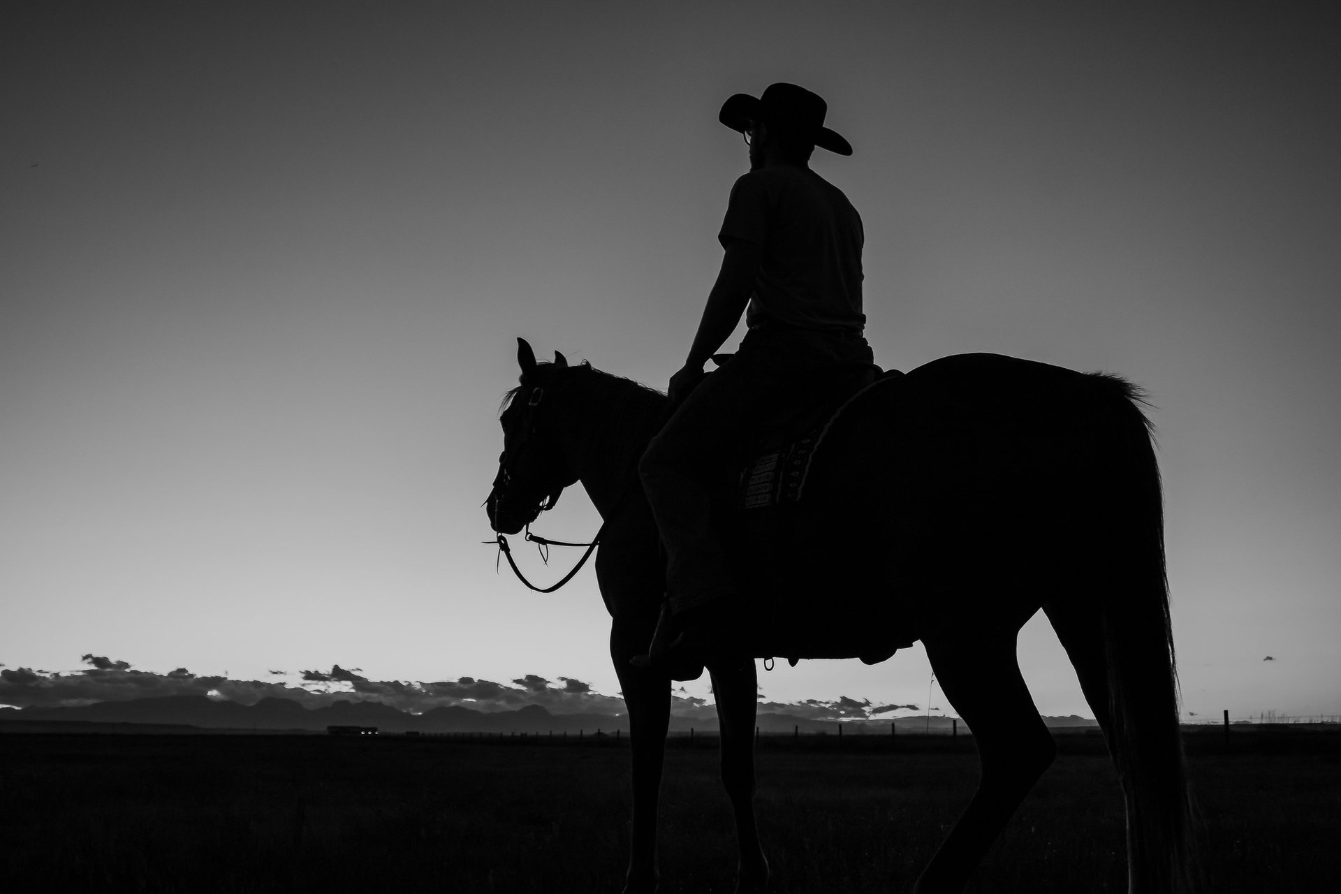 a silhouette of a man in a cowboy hat riding a horse