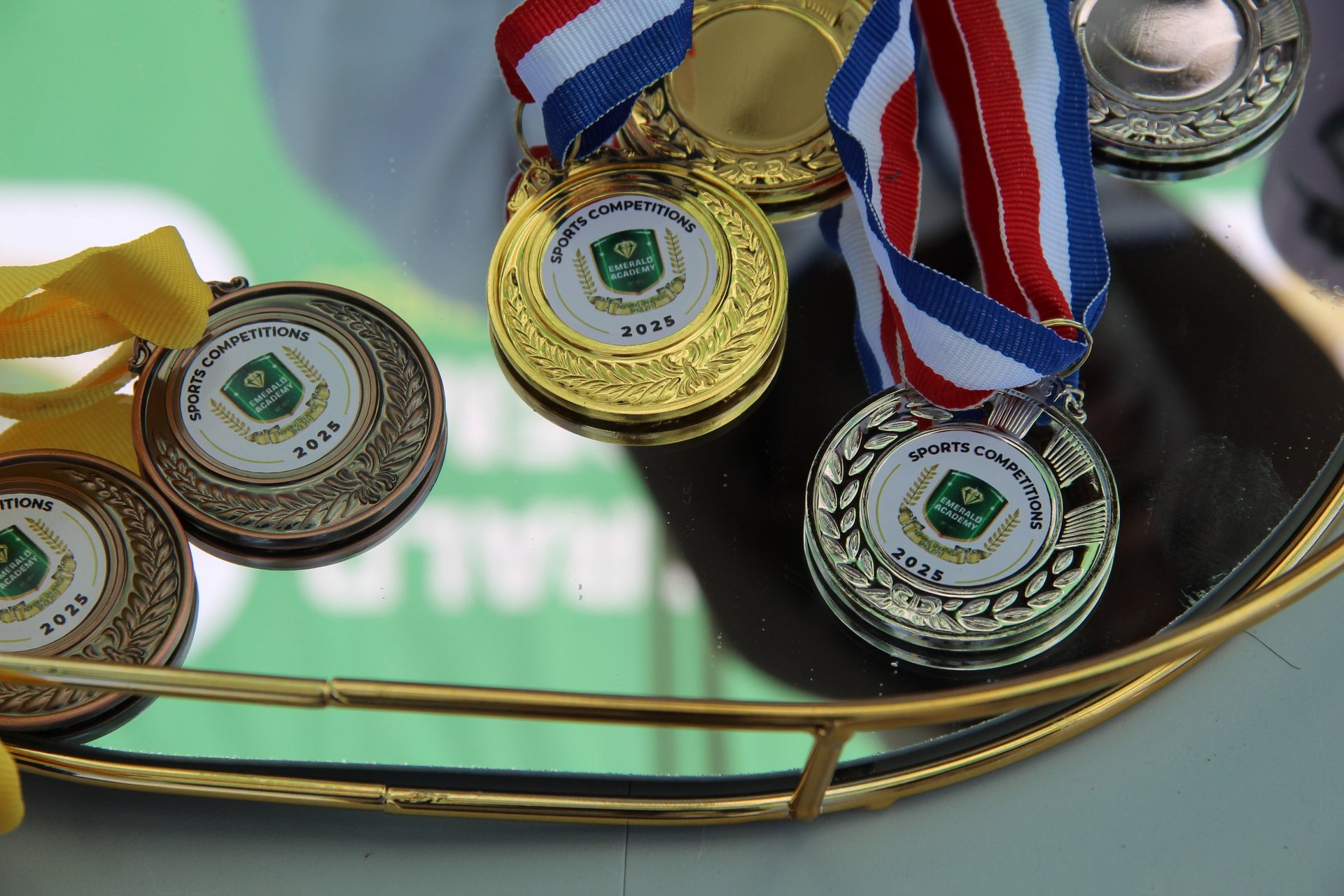 Gold, silver, and bronze sports competition medals for 2025 winners displayed on a tray.