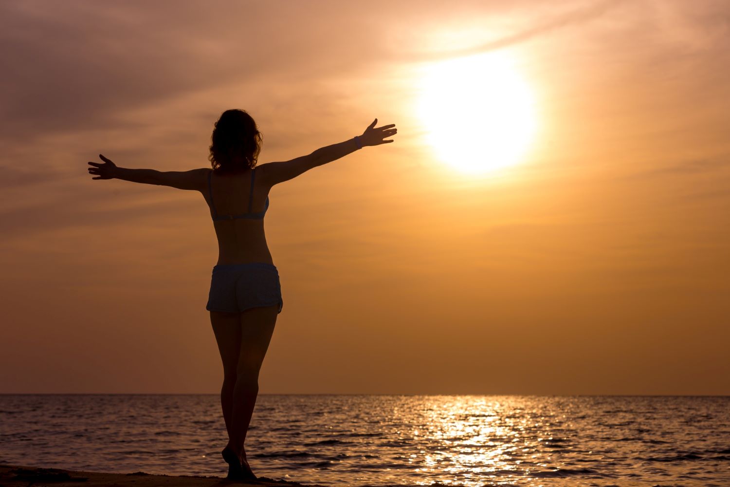 femme libre et heureuse et sereine qui regarde l'horizon en levant les bras