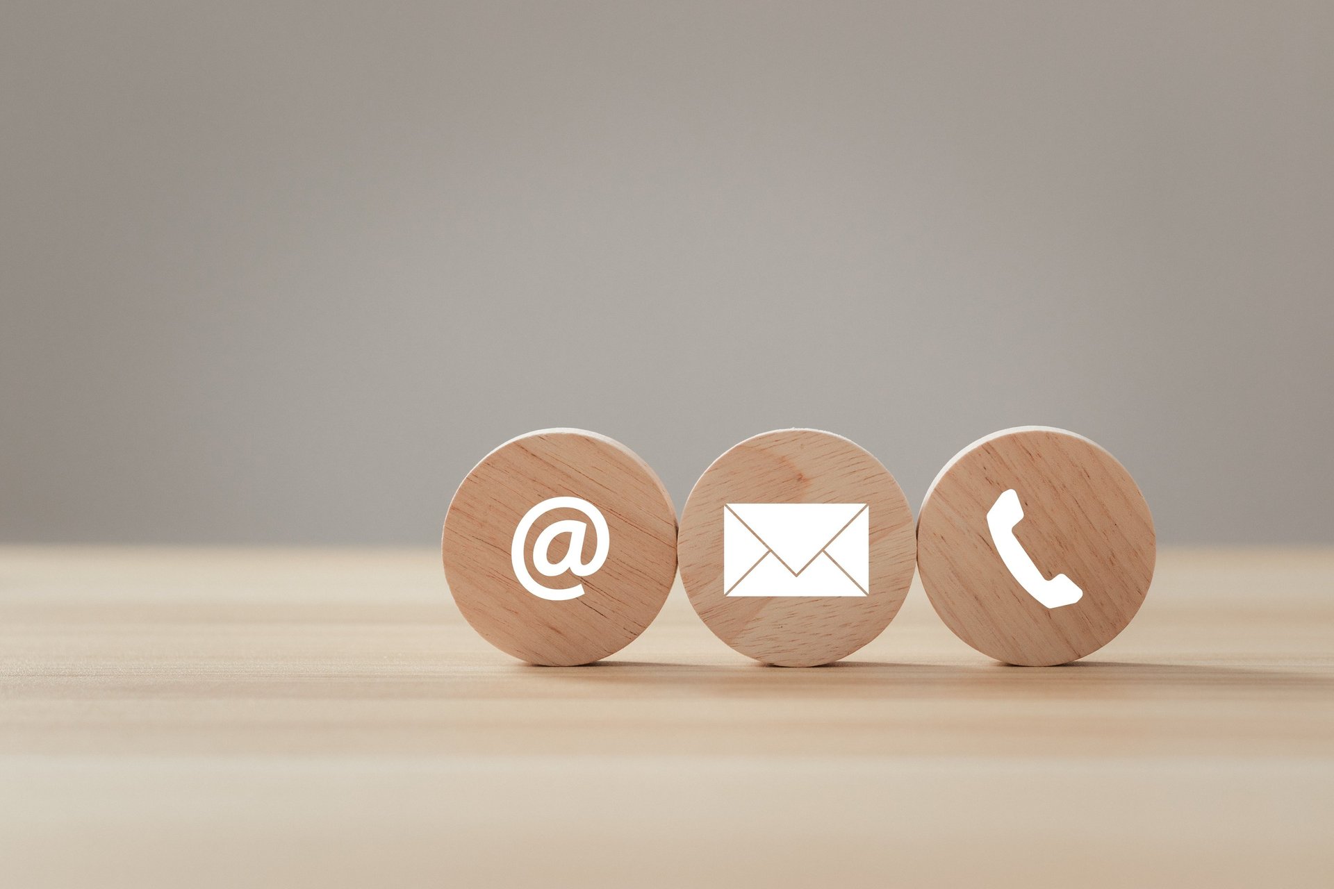 Wooden blocks with email, phone, and at symbols representing contact us options for customer support.