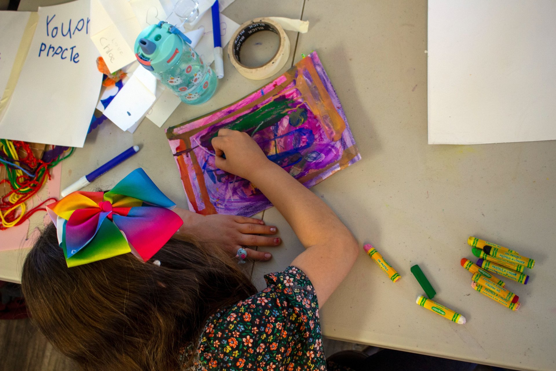 Young child using pastels to create a colorful piece of art on paper.