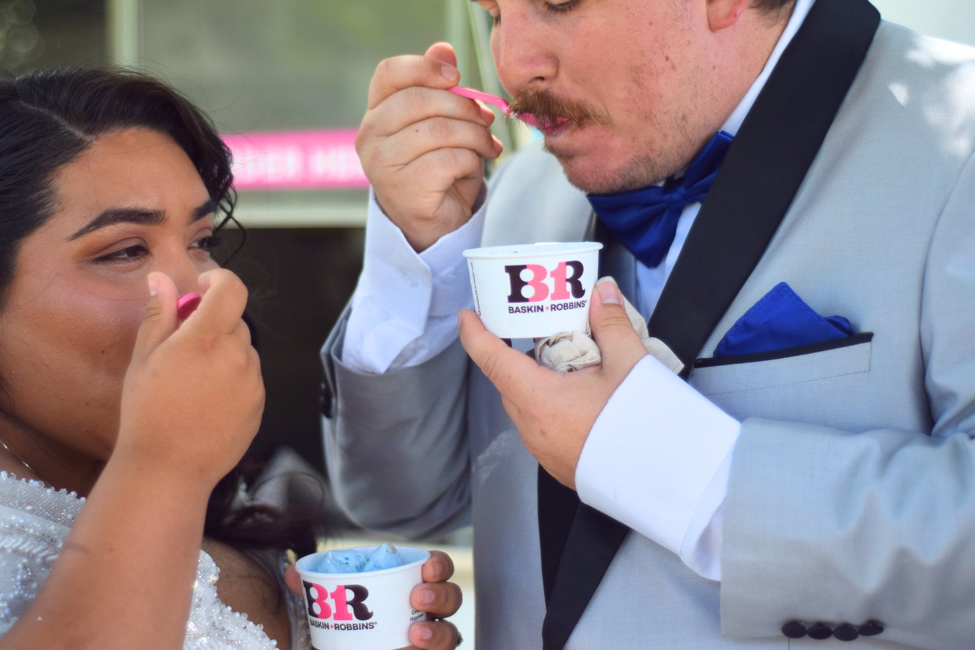 Close-up of a wedding couple in a dress and gray tuxedo enjoying BR Sweet Events ice cream 