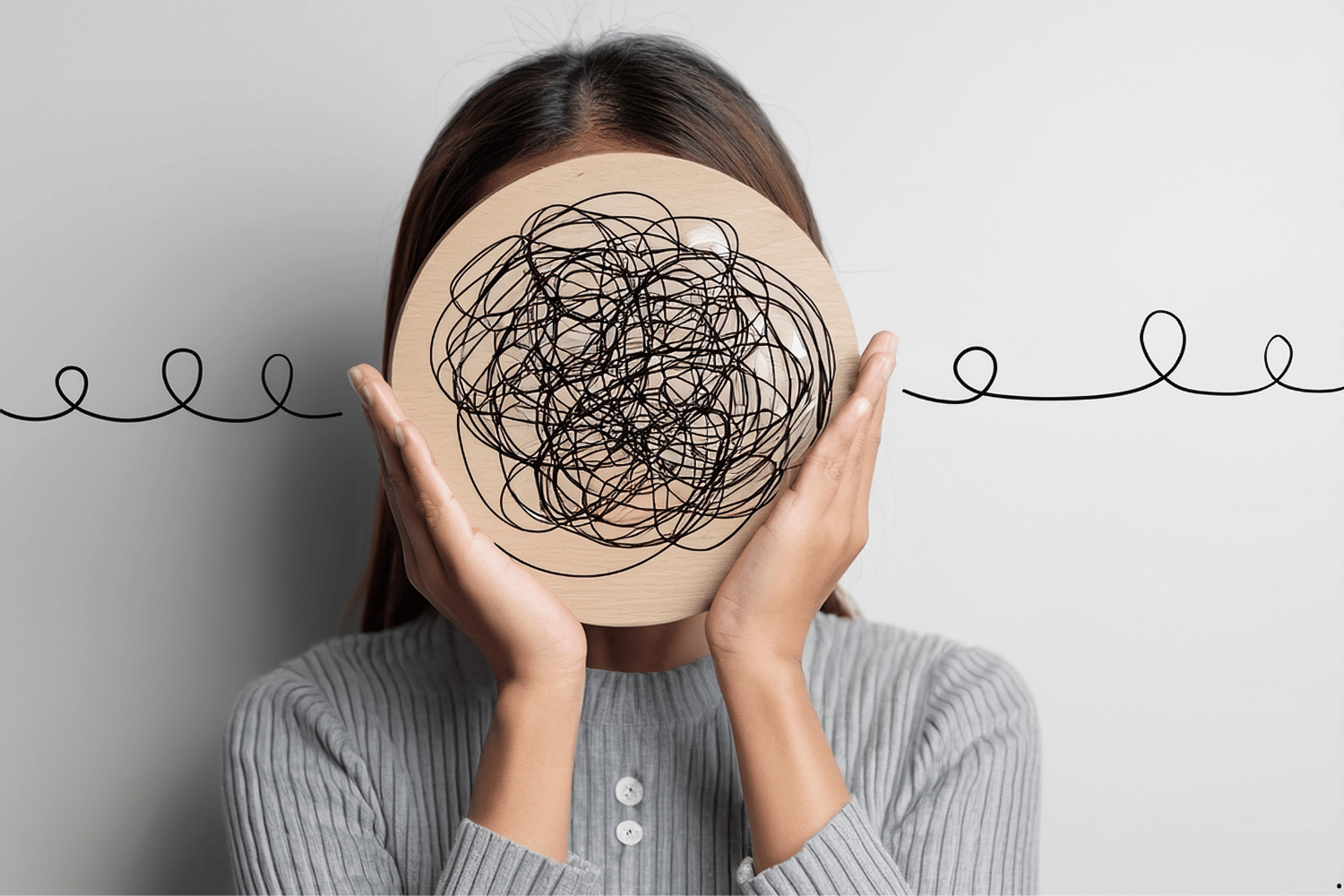 Woman holding a wooden circle with tangled scribbles symbolizing mental health, anxiety, and complex thoughts.