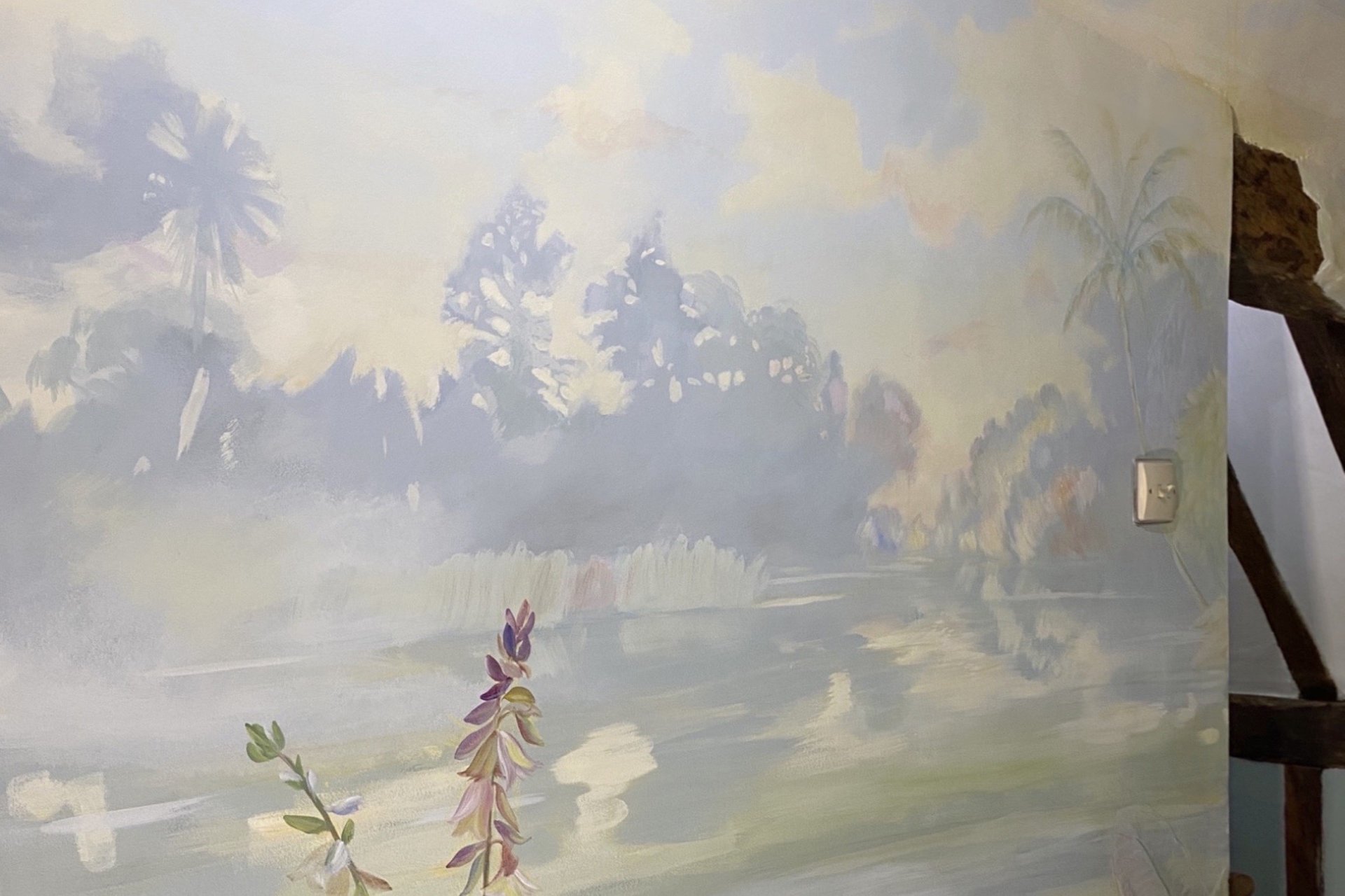 Hand-painted landscape mural with lagoon and trees on interior staircase wall