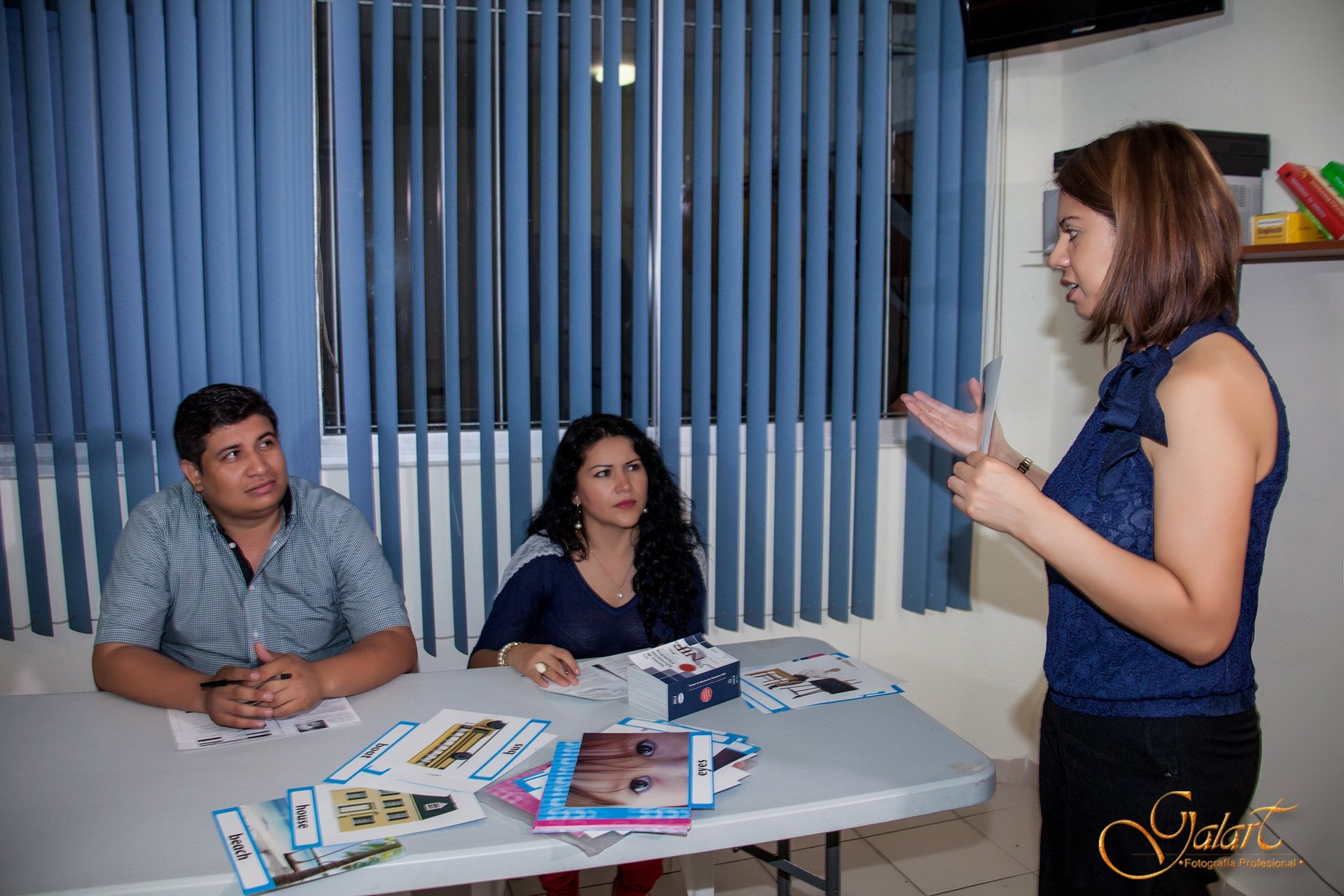 a woman standing in front of a table with a man in a blue shirt
