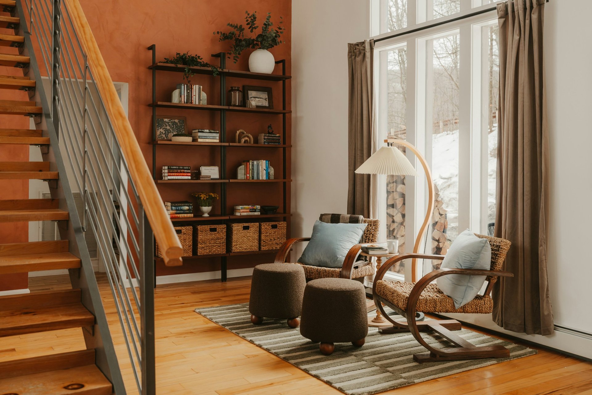 Warm modern living room with staircase, wooden shelving, and lounge seating