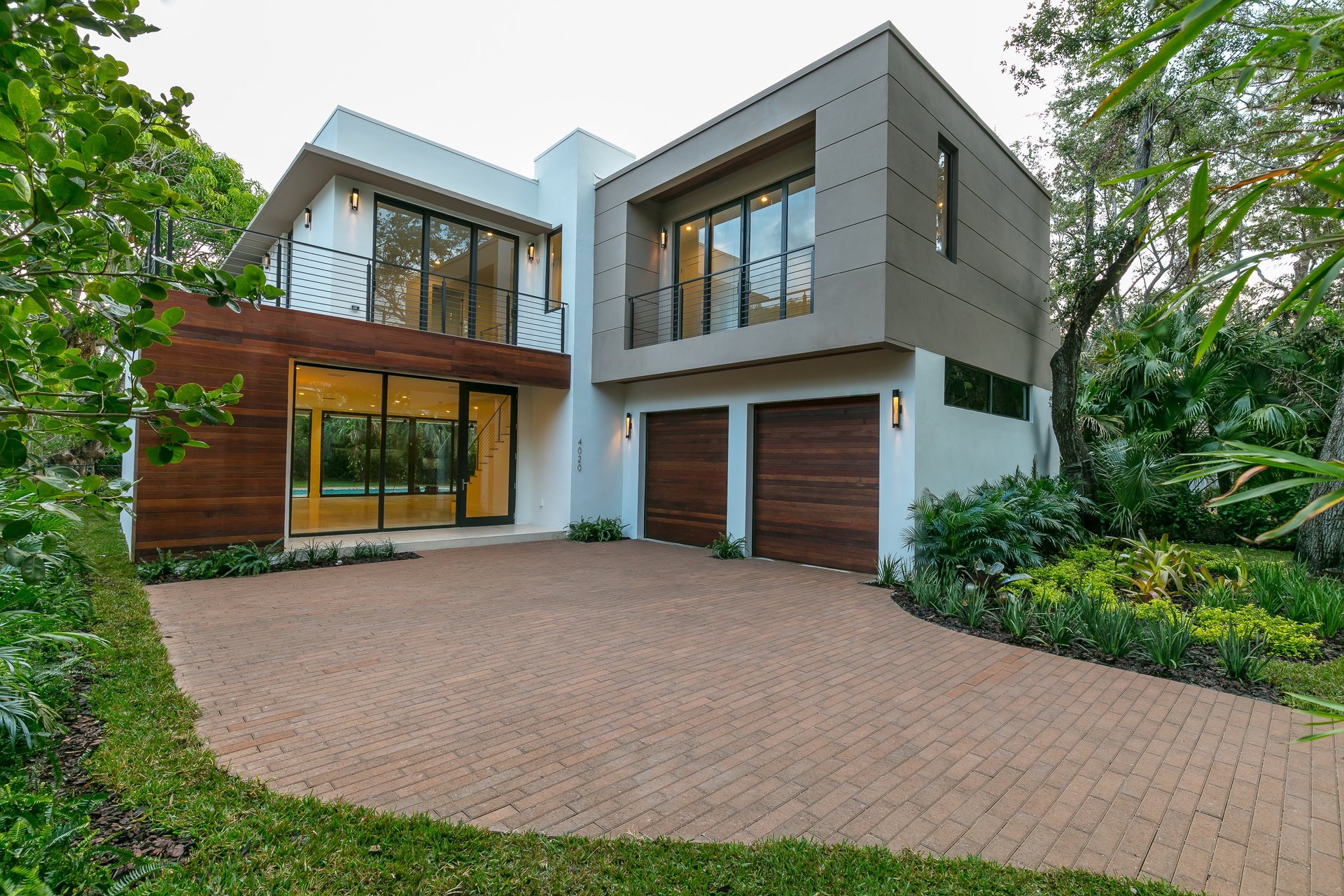 a brick driveway to a square looking custom designed luxury home