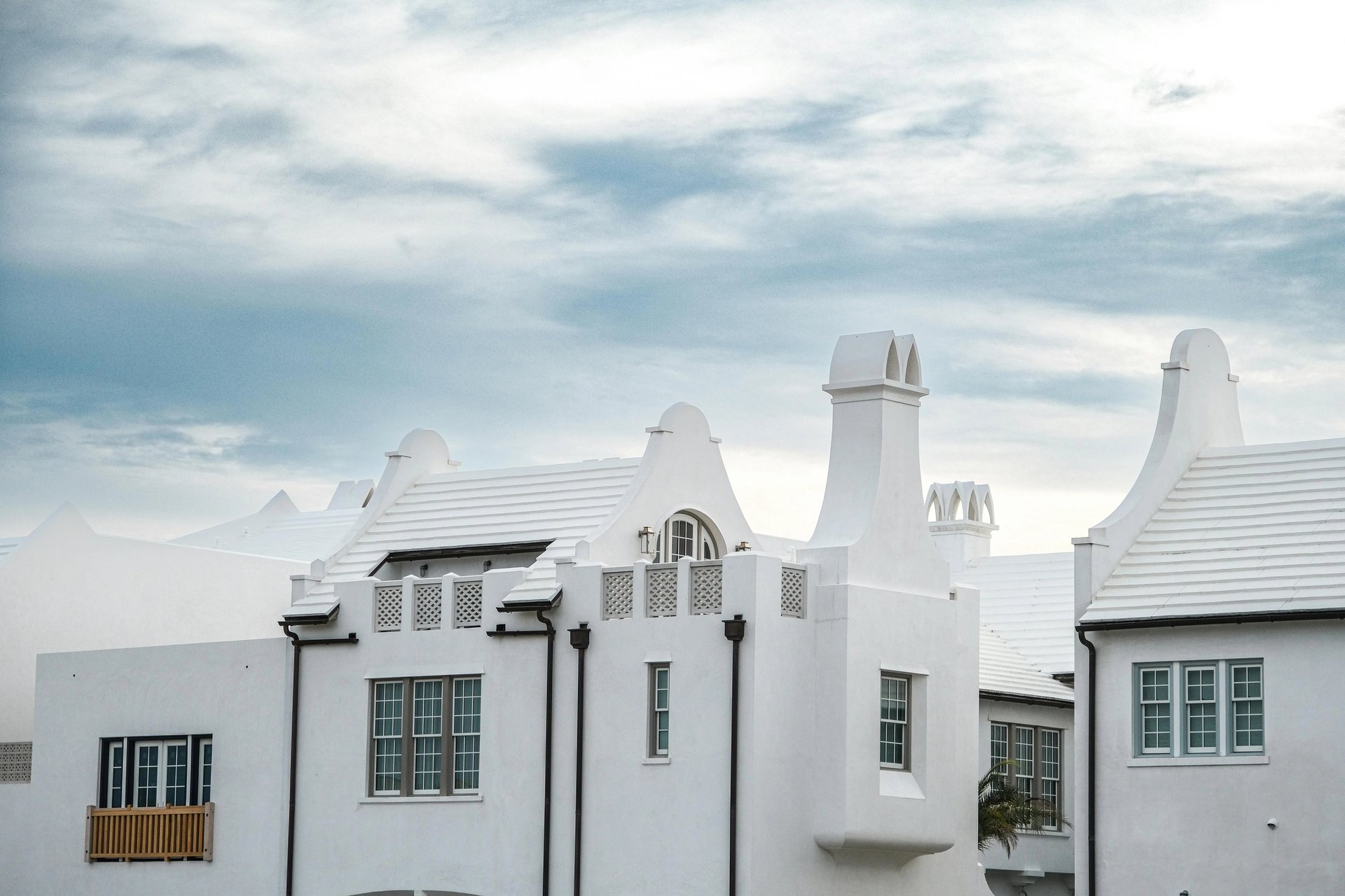 White stucco coastal architecture with iconic stepped chimneys and tile roofs under a cloudy sky.