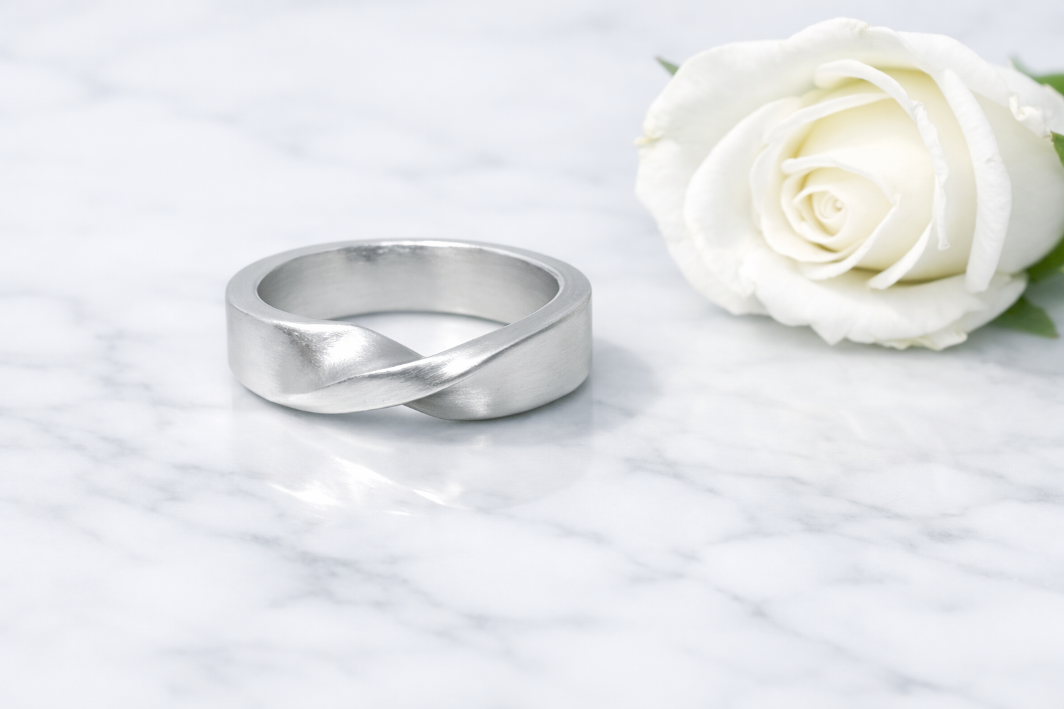 Handcrafted silver rings with smooth, minimalist finishes on a marble surface