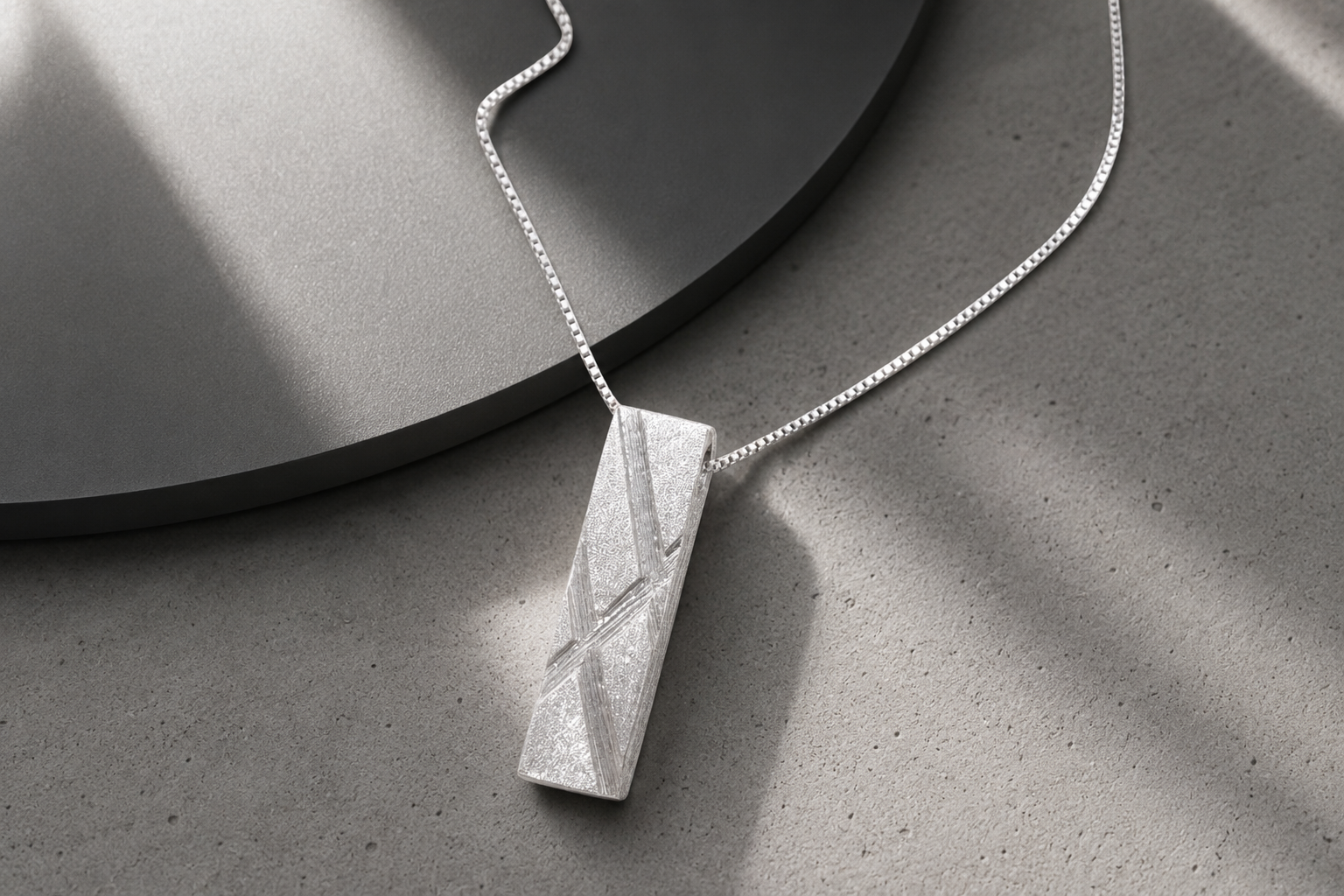 Handcrafted modern 999 fine silver pendant necklace displayed on a white marble surface.