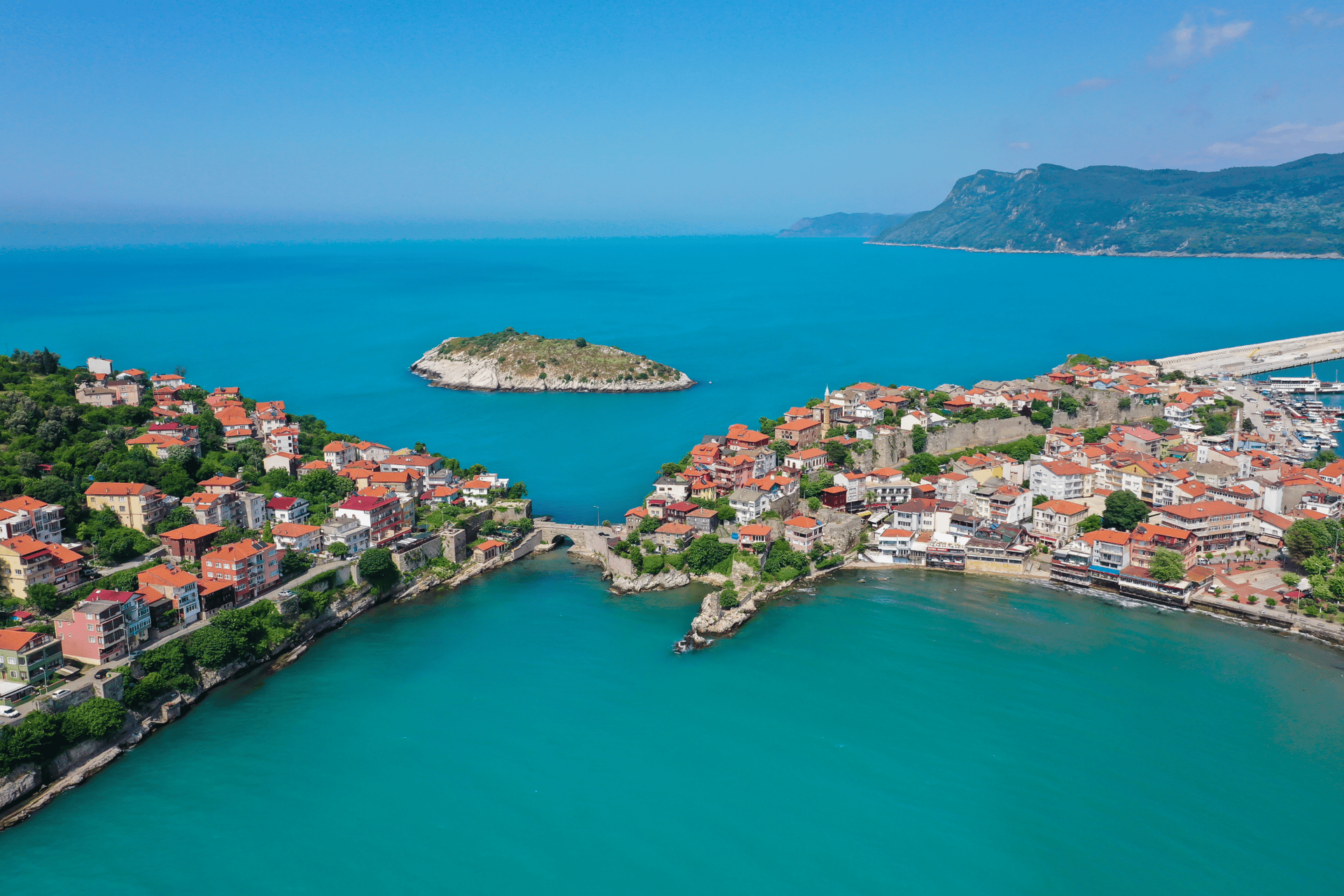 Aerial view of Amasra coastal town with historic red-roofed houses and turquoise Black Sea water.