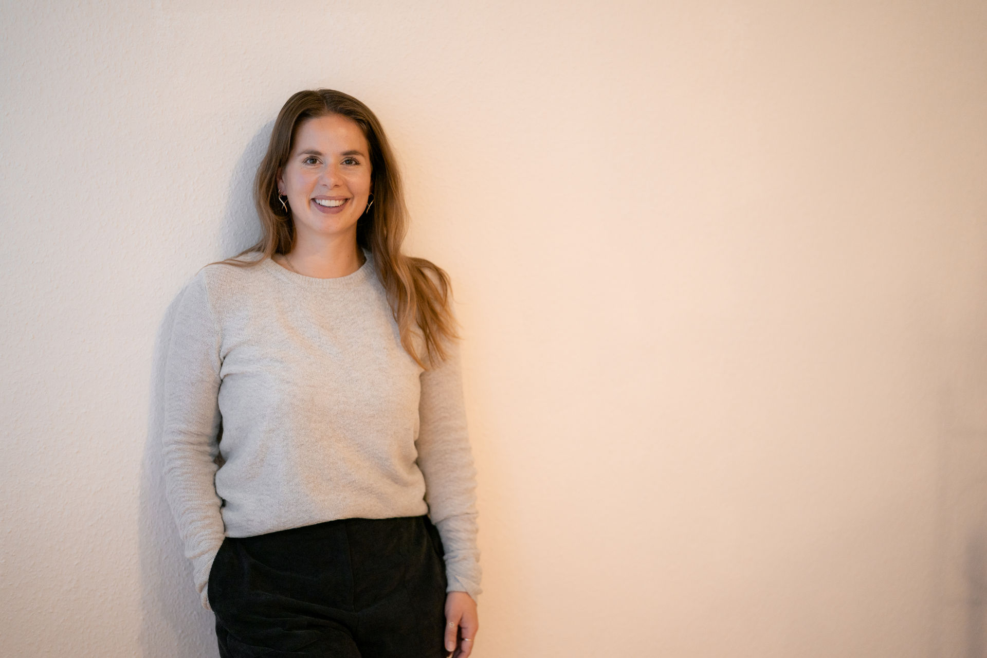 Frau lehnt an der Wand und stellt sich als kompetente Beraterin vor