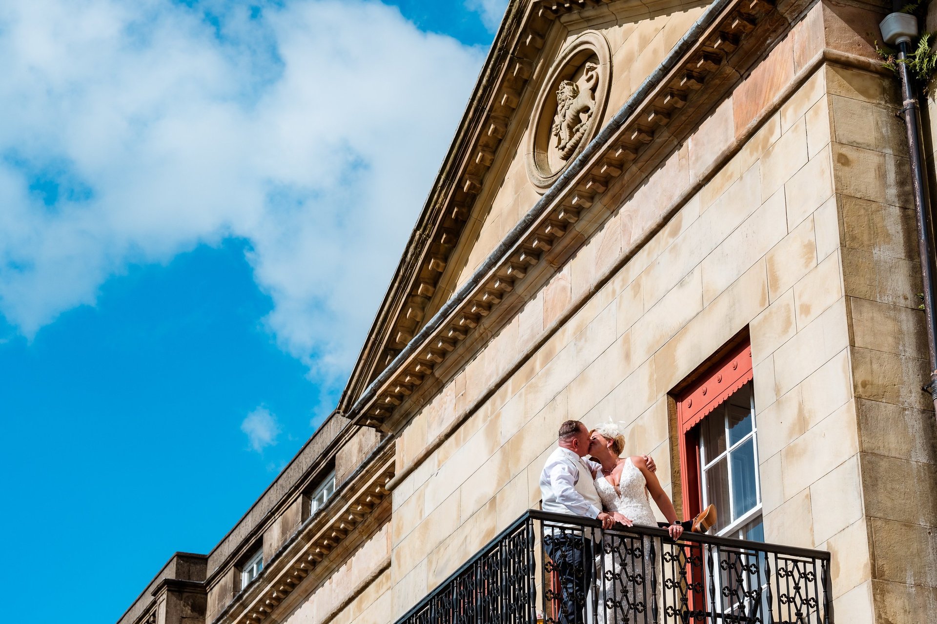 a bride and groom kissing on a balcony balcony