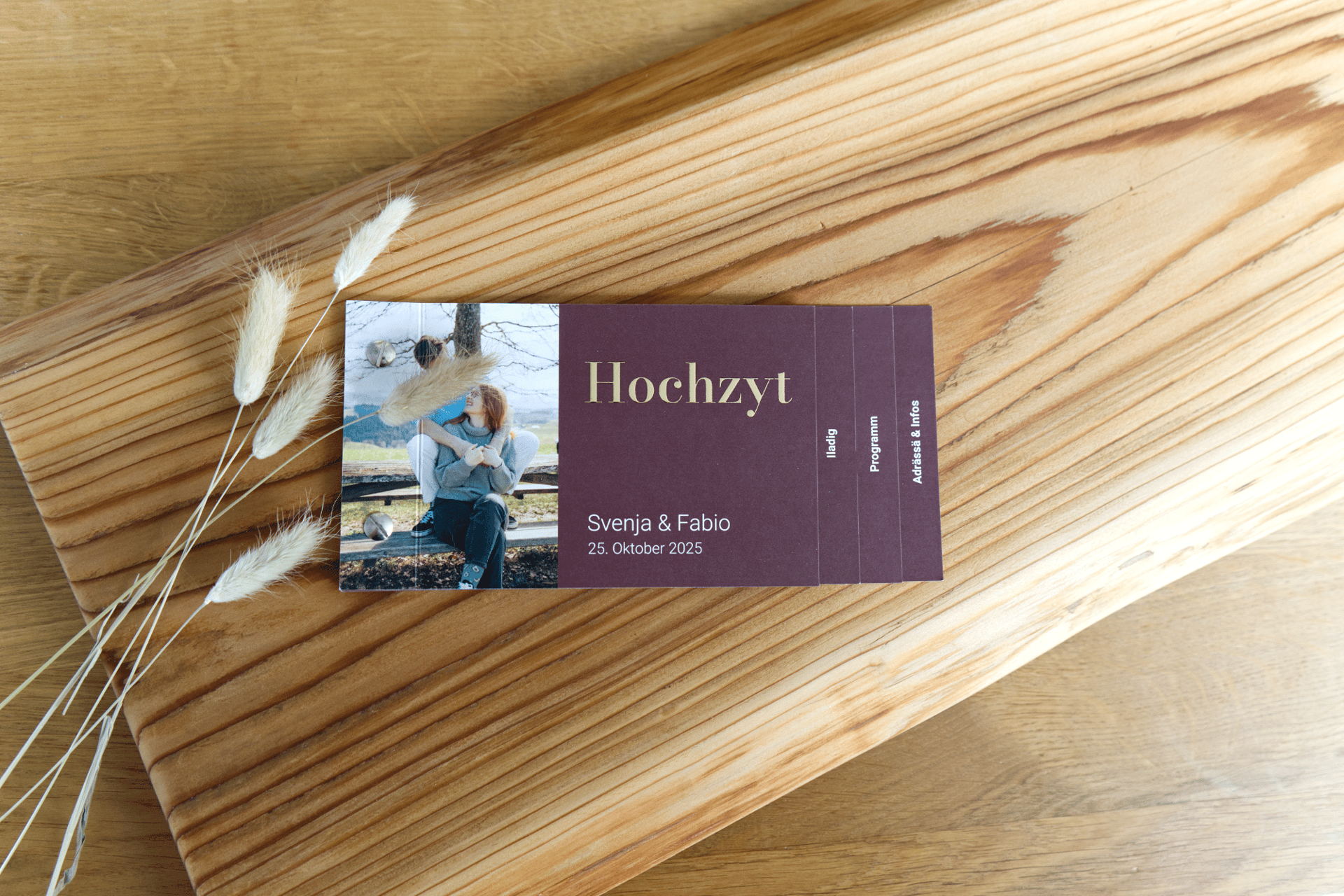 Hochzeitseinladungskarte mit einem Foto des Paares vor einem rustikalen Holzbrett-Hintergrund.
