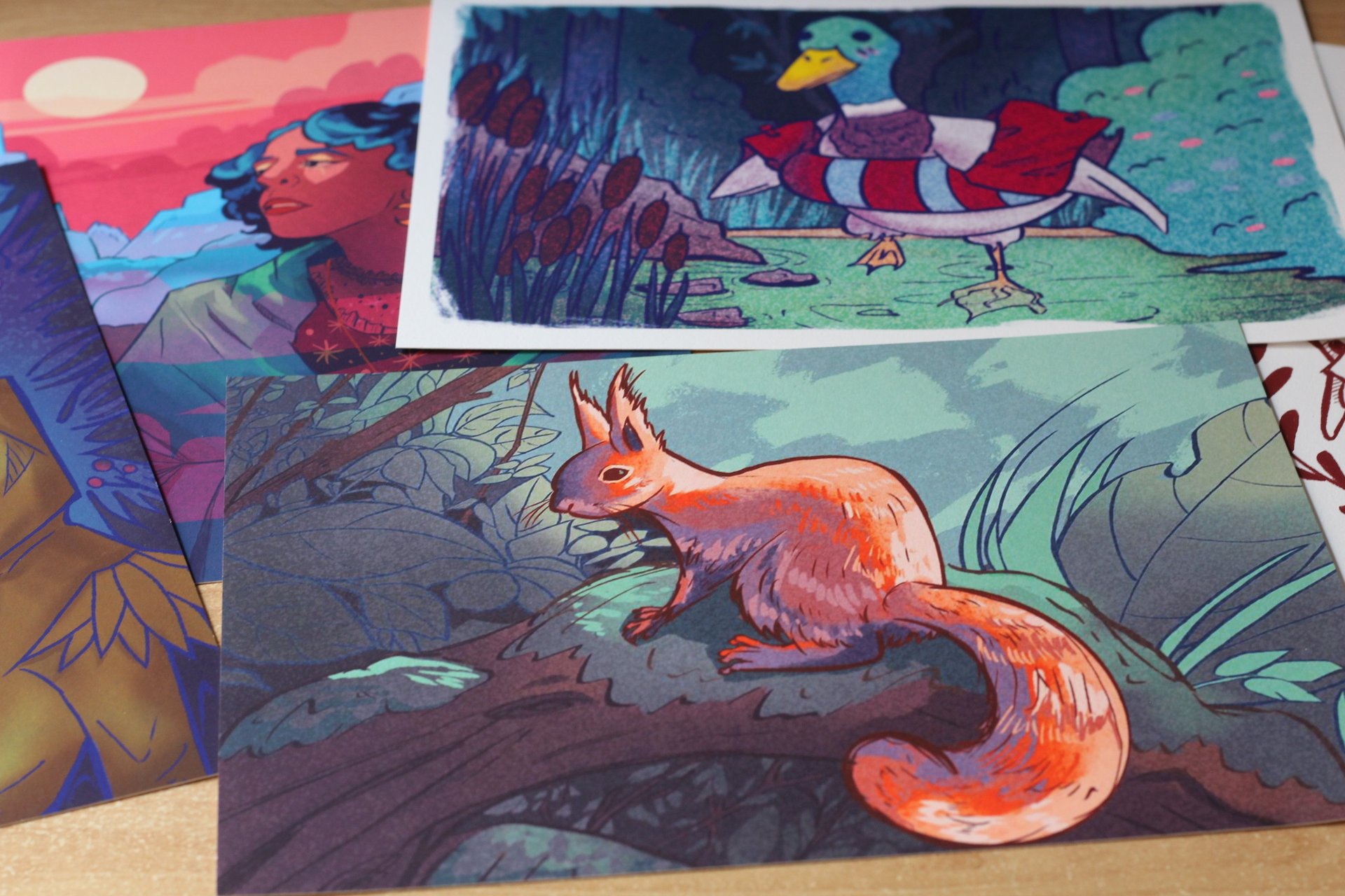 Art prints scattered.Illustra animal illustrations include a squirrel, a duck and a woman.