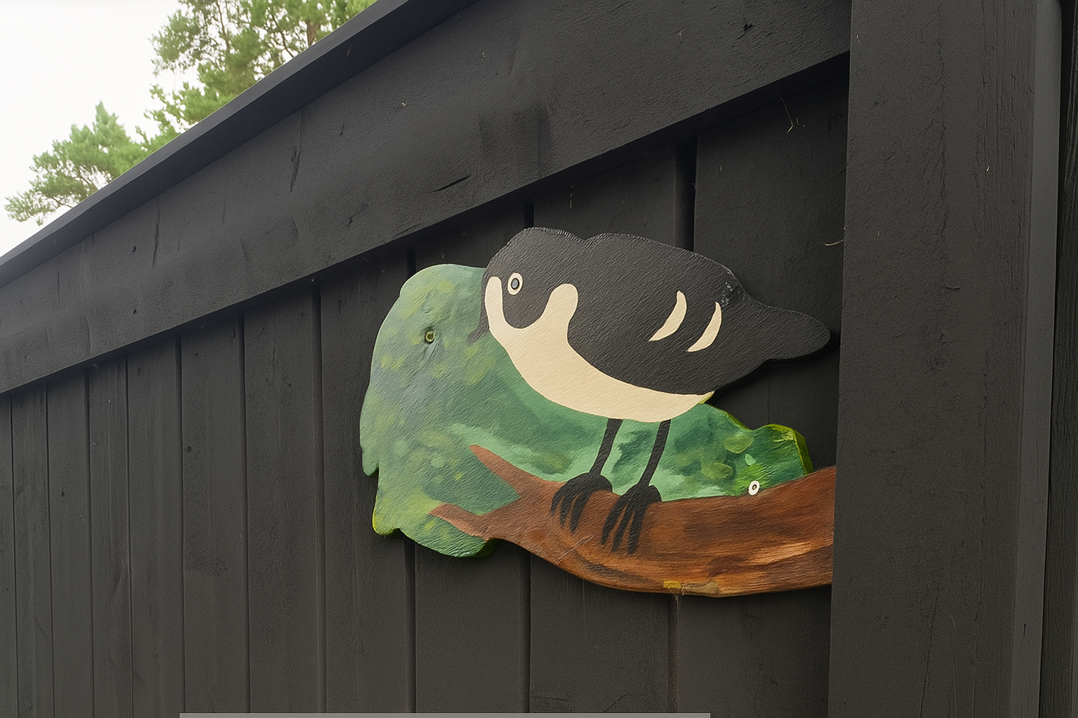 une cloture noire en peinture bois brule avec un oiseau peint pour decorer
