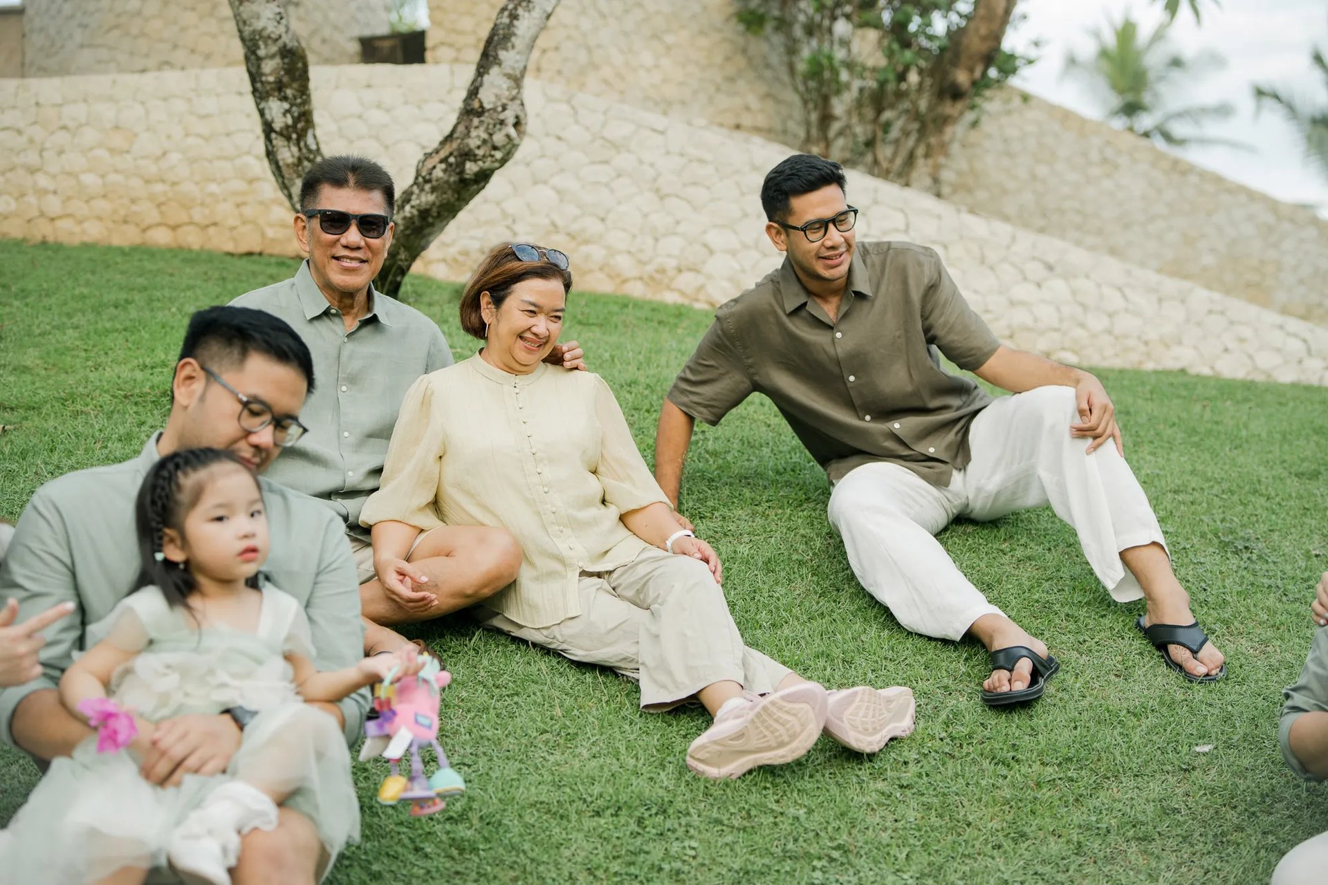 Three generation family relaxing together on a tropical garden lawn during a family photography session in Bali.