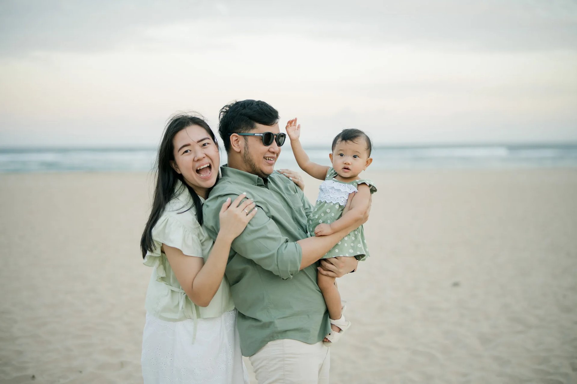 Parents holding their daughter during a natural family photography session on the beach in Bali.
