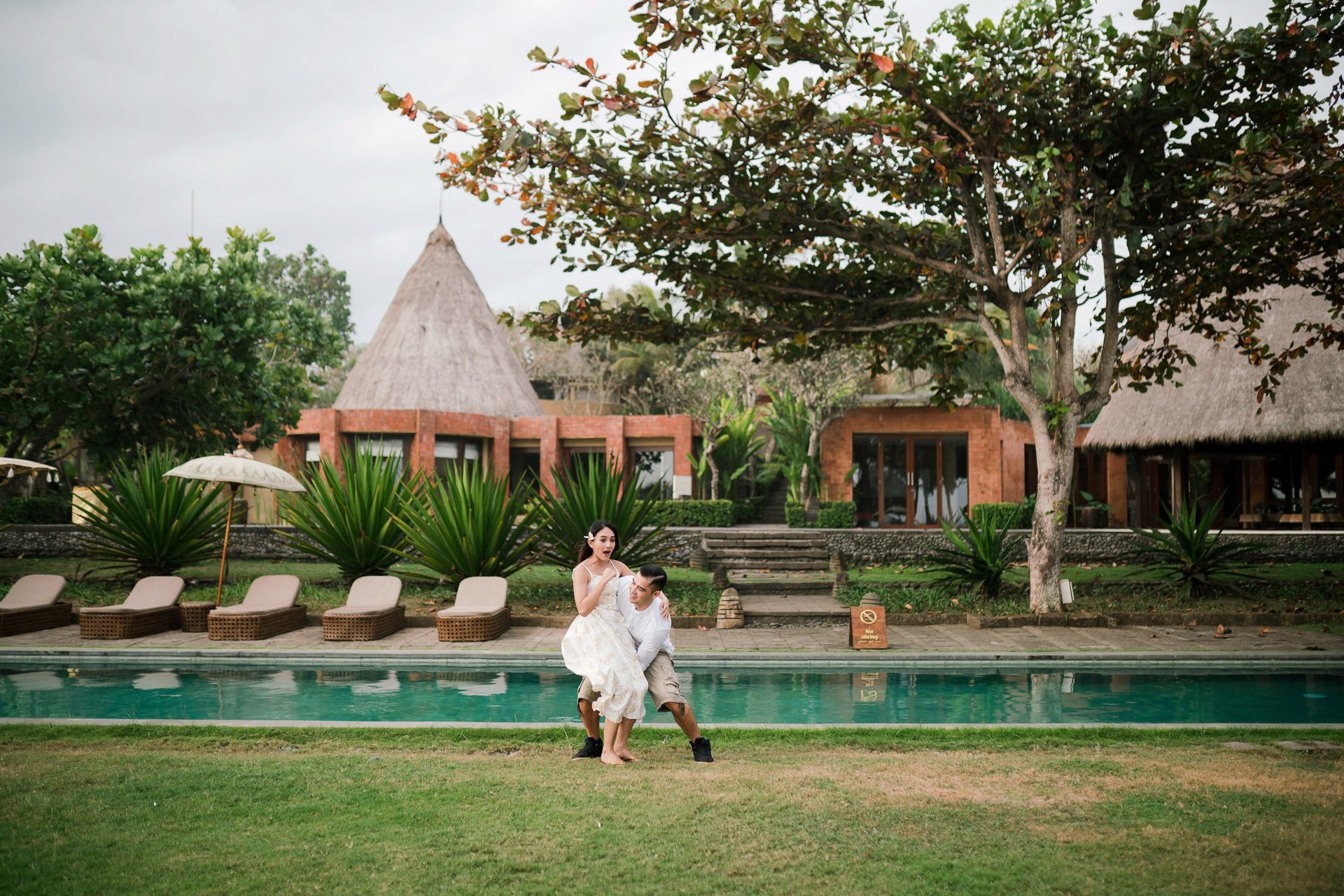 Couple standing by the pool at Waka Gangga Tabanan surrounded by tropical architecture in West Bali