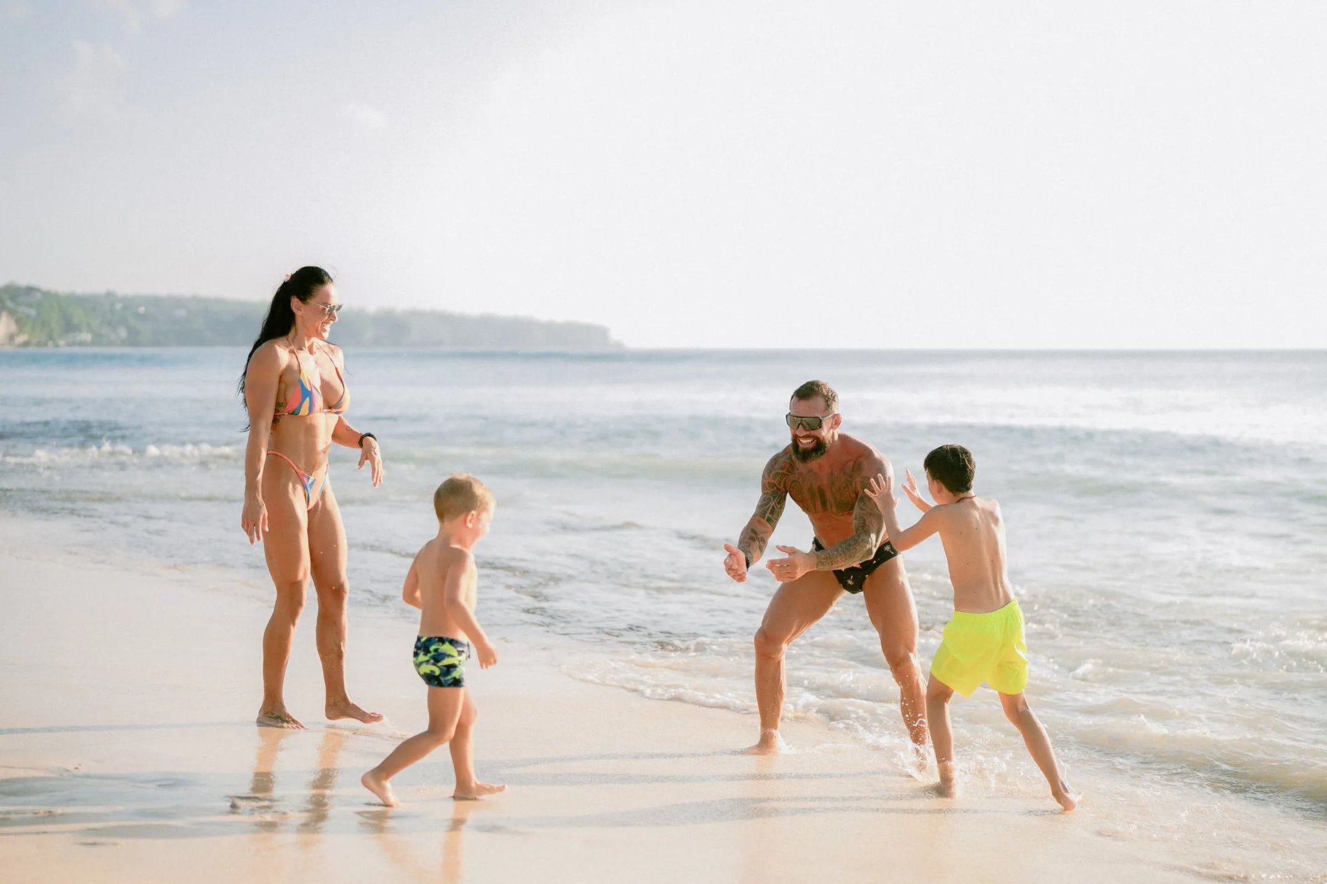 Children playing in the shoreline waves during a fun family beach photography session at Dreamland Beach Bali.