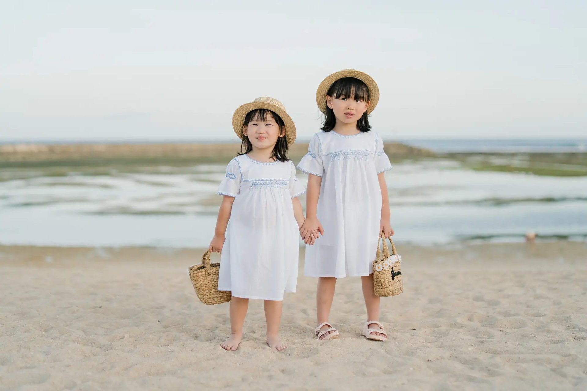 Two sisters standing together on the beach at The Apurva Kempinski Bali.
