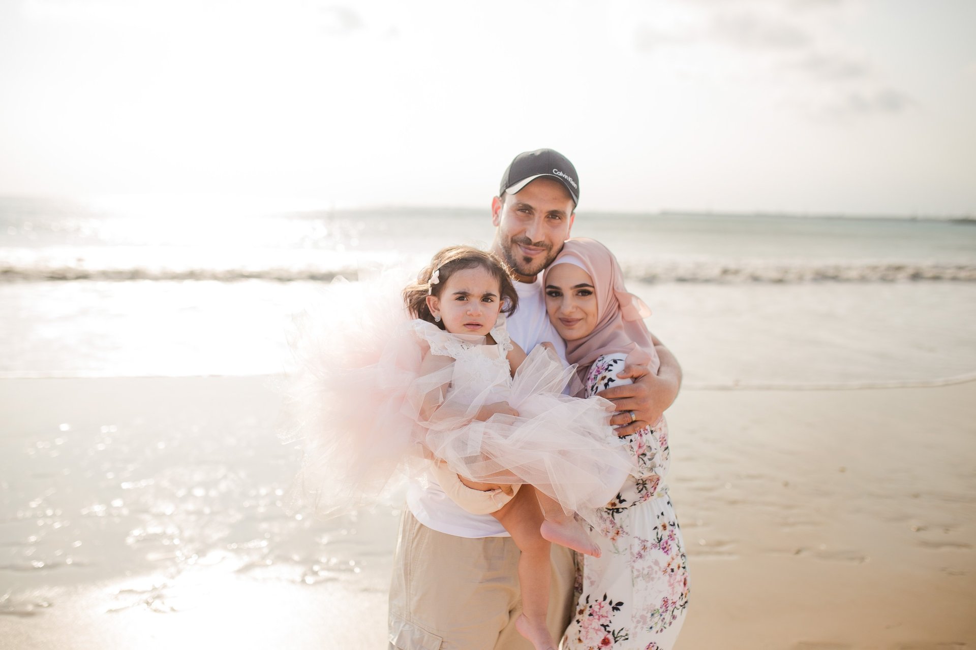 family photography Jimbaran Beach Bali parents holding child by the sea