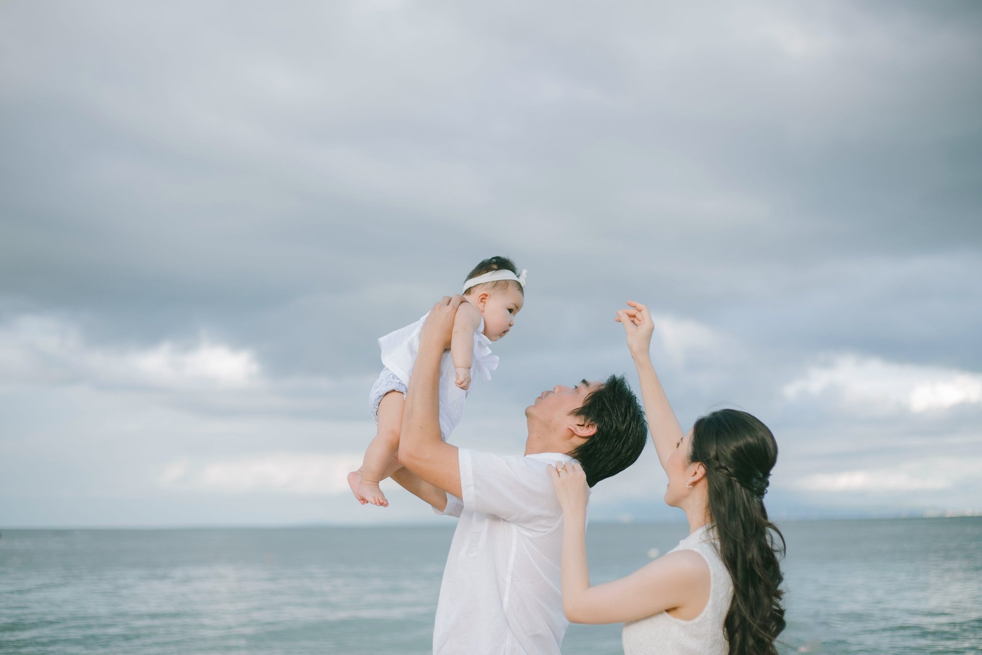 Father lifting baby near the ocean during family photography session at Sofitel Nusa Dua Bali