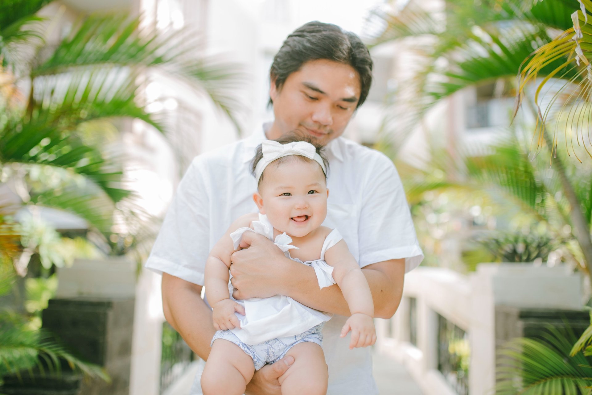 Father holding baby in tropical garden during family photography session at Sofitel Nusa Dua Bali