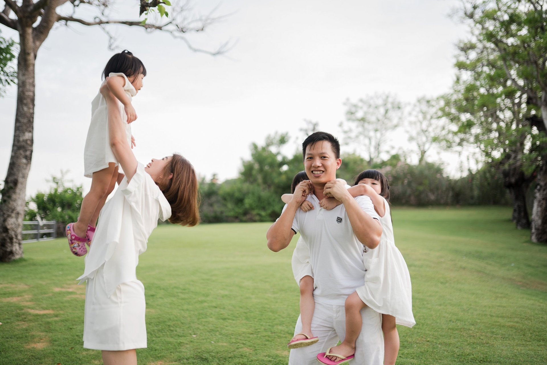 Mother lifting daughter playfully during a family photography session on the lawn at The Mulia Nusa Dua Bali