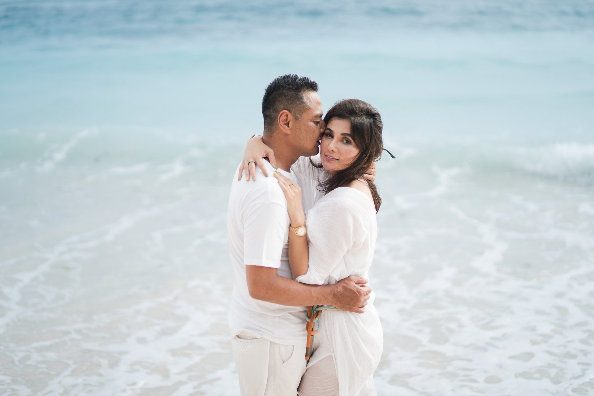 Couple embracing by the ocean during a beach session at Karma Kandara Bali  