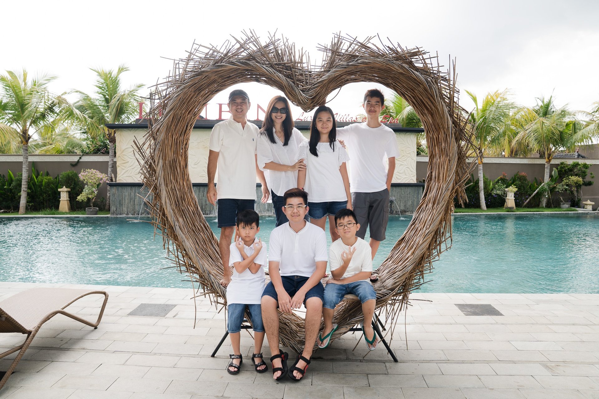 Family portrait inside heart frame during extended family photography at Lumbini Villas Jimbaran Bali by the pool