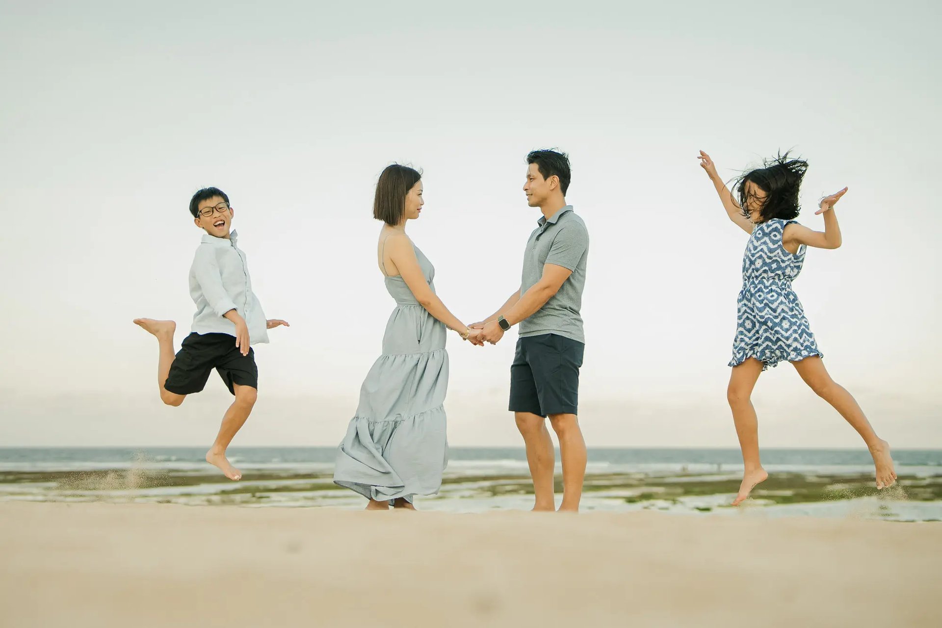 Family holding hands and walking together during a beach photography session at The Ritz-Carlton Bali.