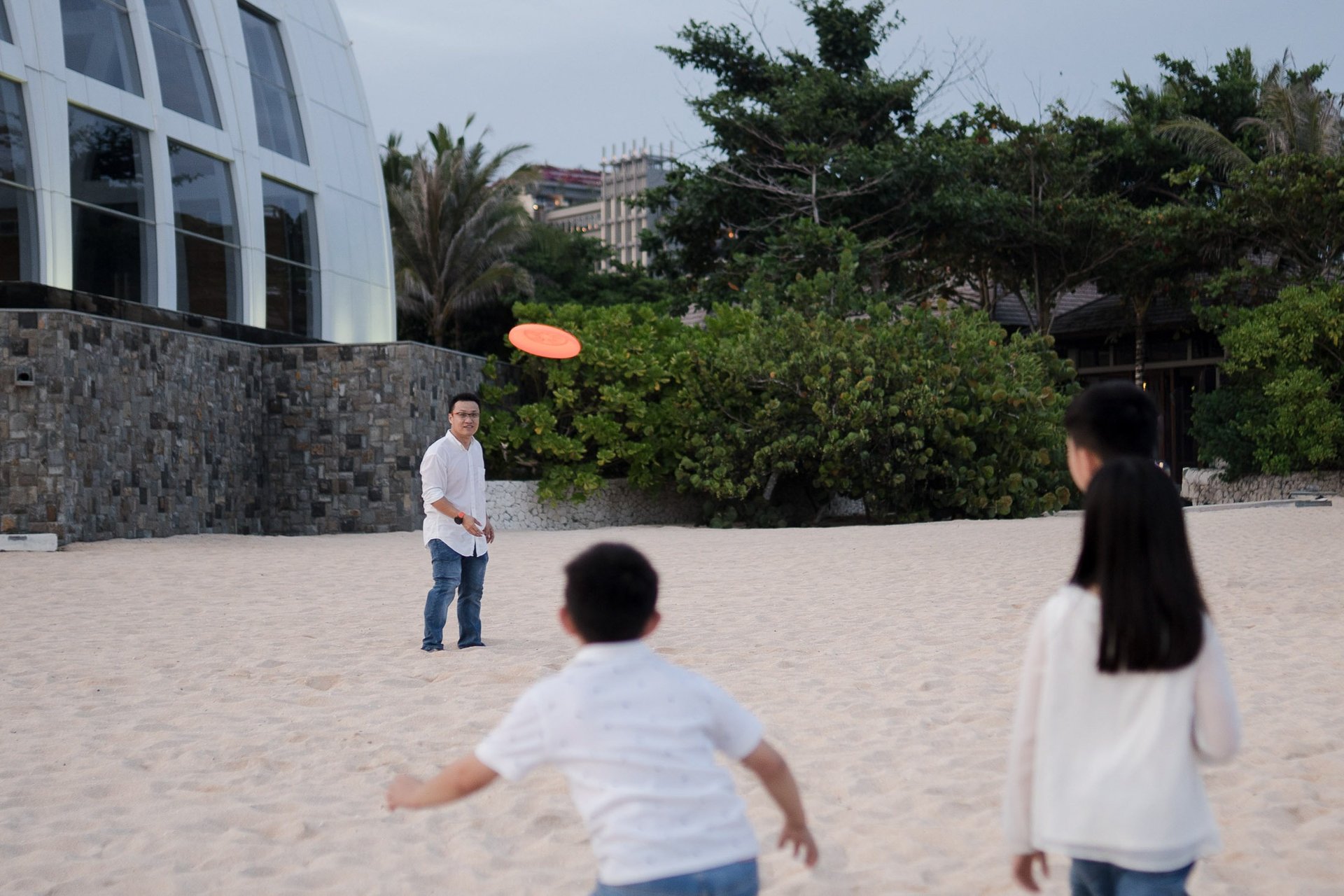 Family enjoying a playful beach moment near the shoreline at The Ritz-Carlton Bali Nusa Dua