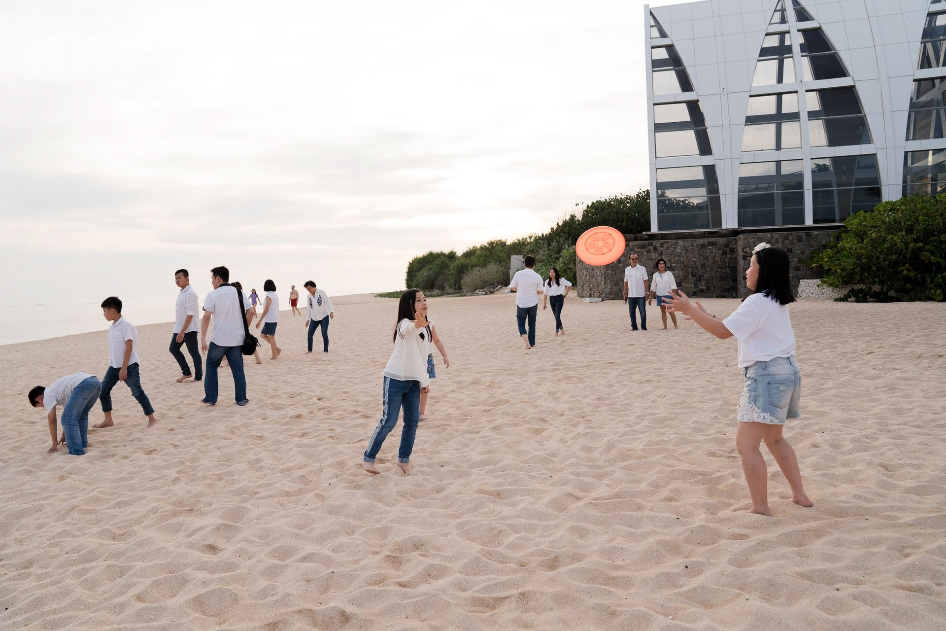 Family playing together on the sandy beach during a relaxed family photography session at The Ritz-Carlton Bali Nusa Dua