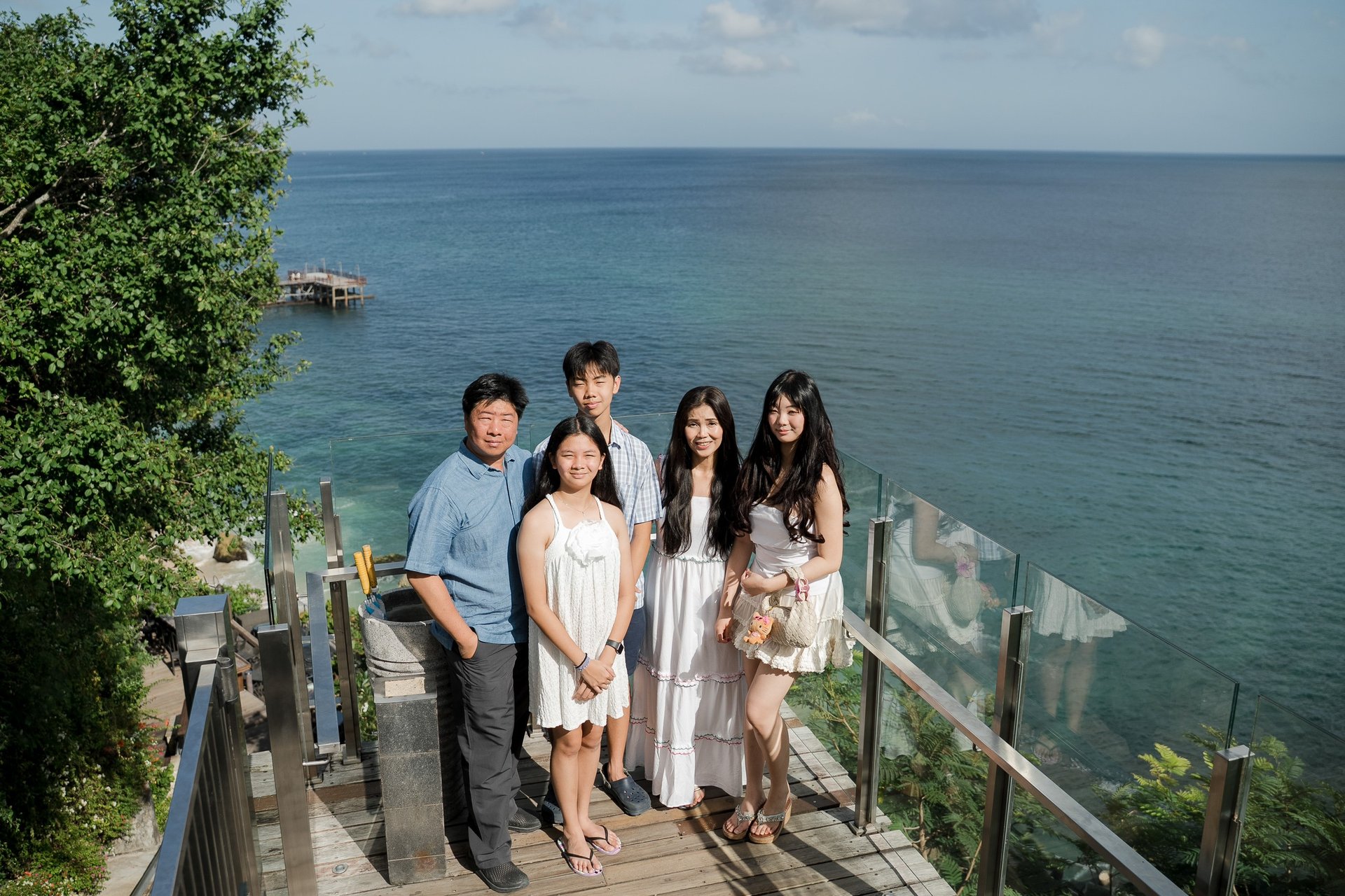 Family standing together overlooking the ocean during a relaxed photography session at Ayana Jimbaran Bali