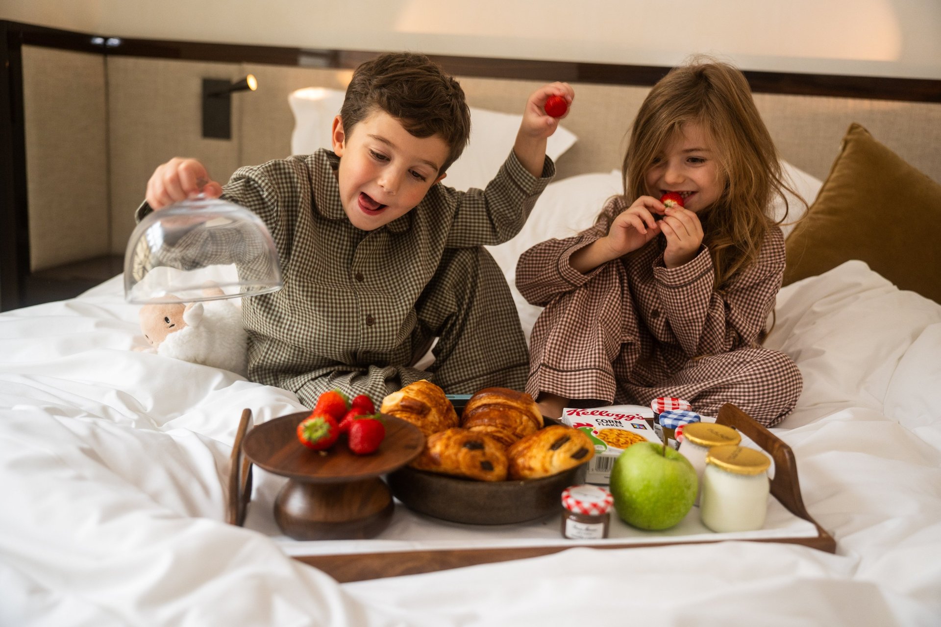 Enfants au petit déjeuner sur un lit de chambre d'hôtel