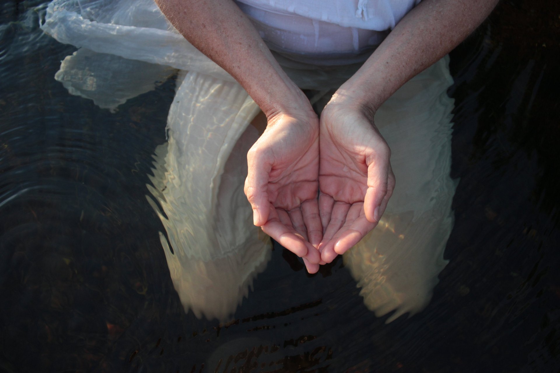 Deux mains sont jointes en coupe dans l'eau.