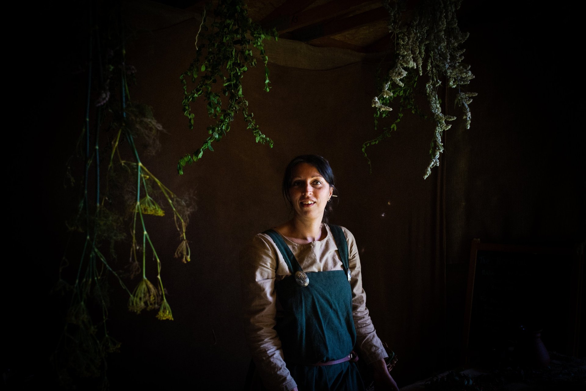 an atmospheric picture of a woman in green viking clothes surrounded by herbal plants