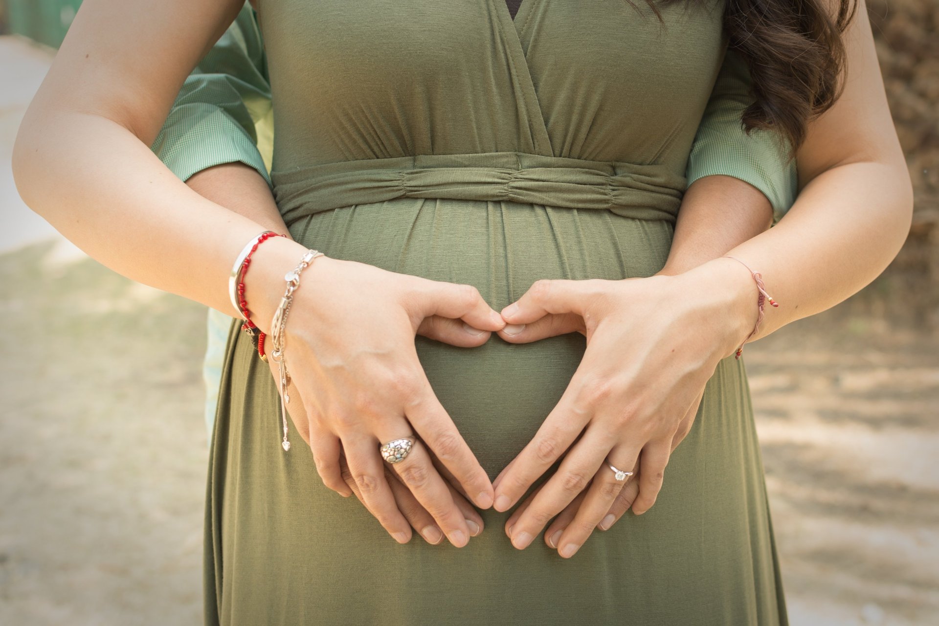 a pregnant woman in a green dress with her hands on her belly