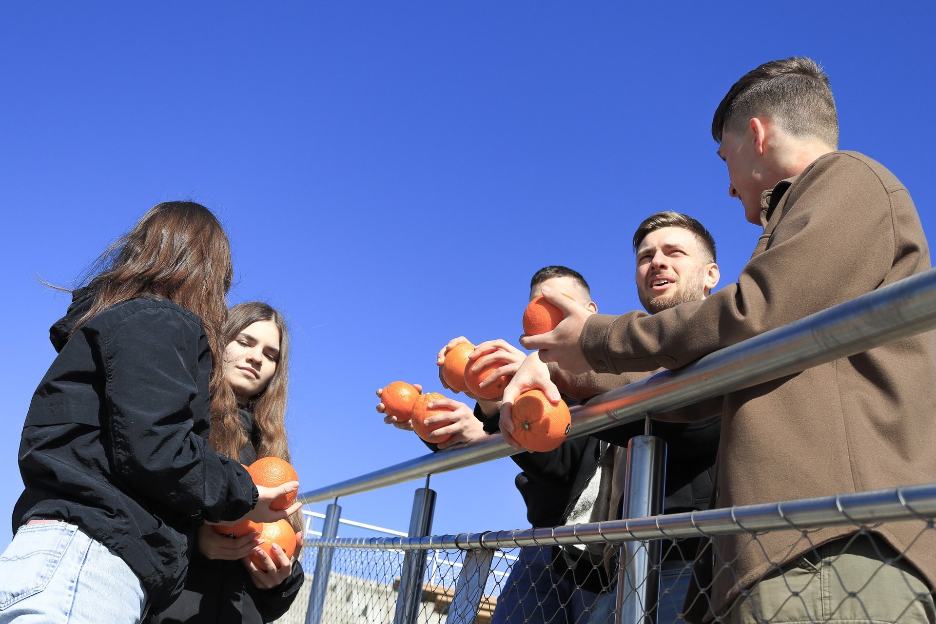 jauni zmones lauke sneka ir rankose laiko apelsinus