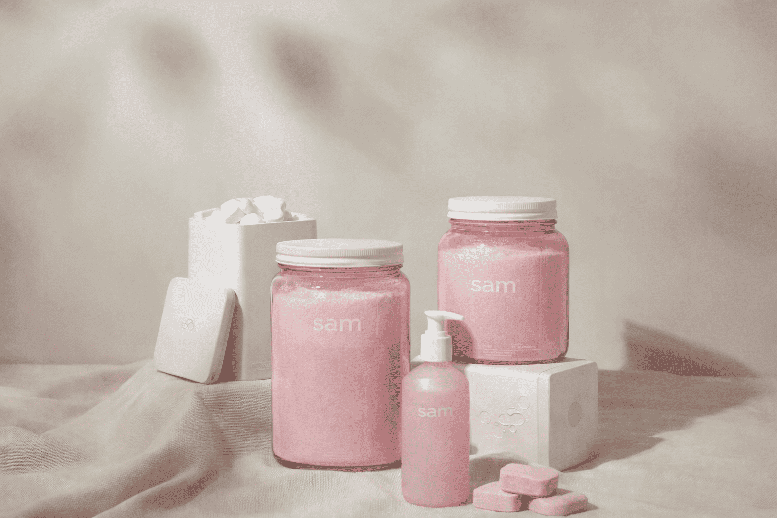 Envases rosa pastel de SAM Cosméticos en colección de belleza elegante y minimalista.