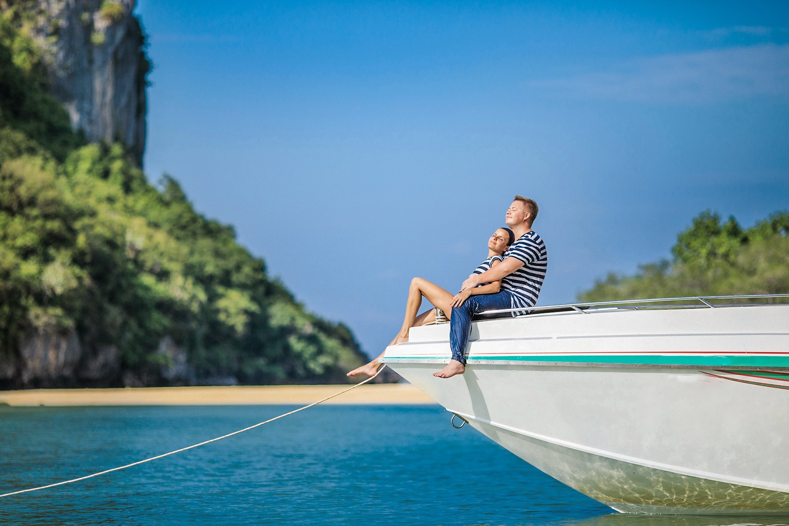 A couple sitting at the edge of a white speedboat, enjoying the sun during their honeymoon on Samui