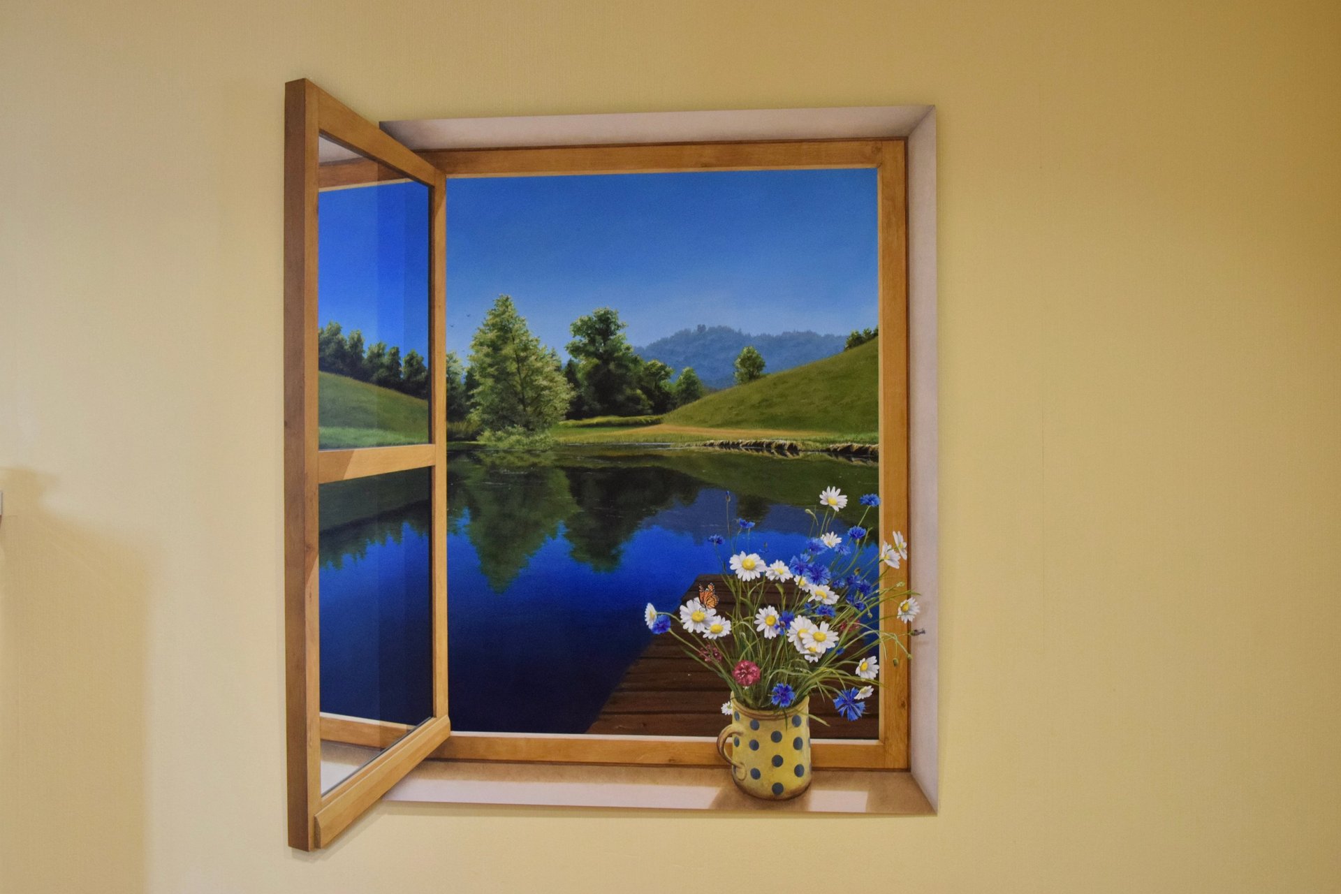 Fenêtre en trompe-l'oeil sur un mur intérieur, donnant l'illusion d'une ouverture sur un paysage.
