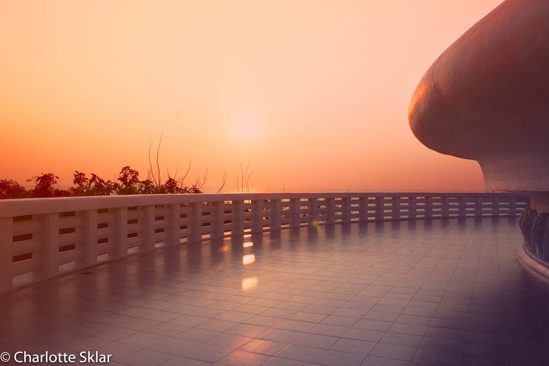 Golden sunset view from a modern white tiled balcony of a temple in Sri Lanka.