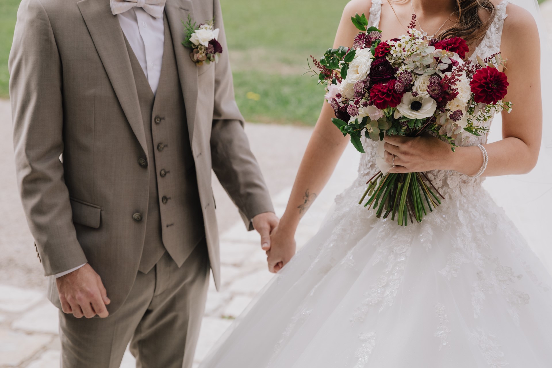 zoom sur mariés se tiennent la main et bouquet