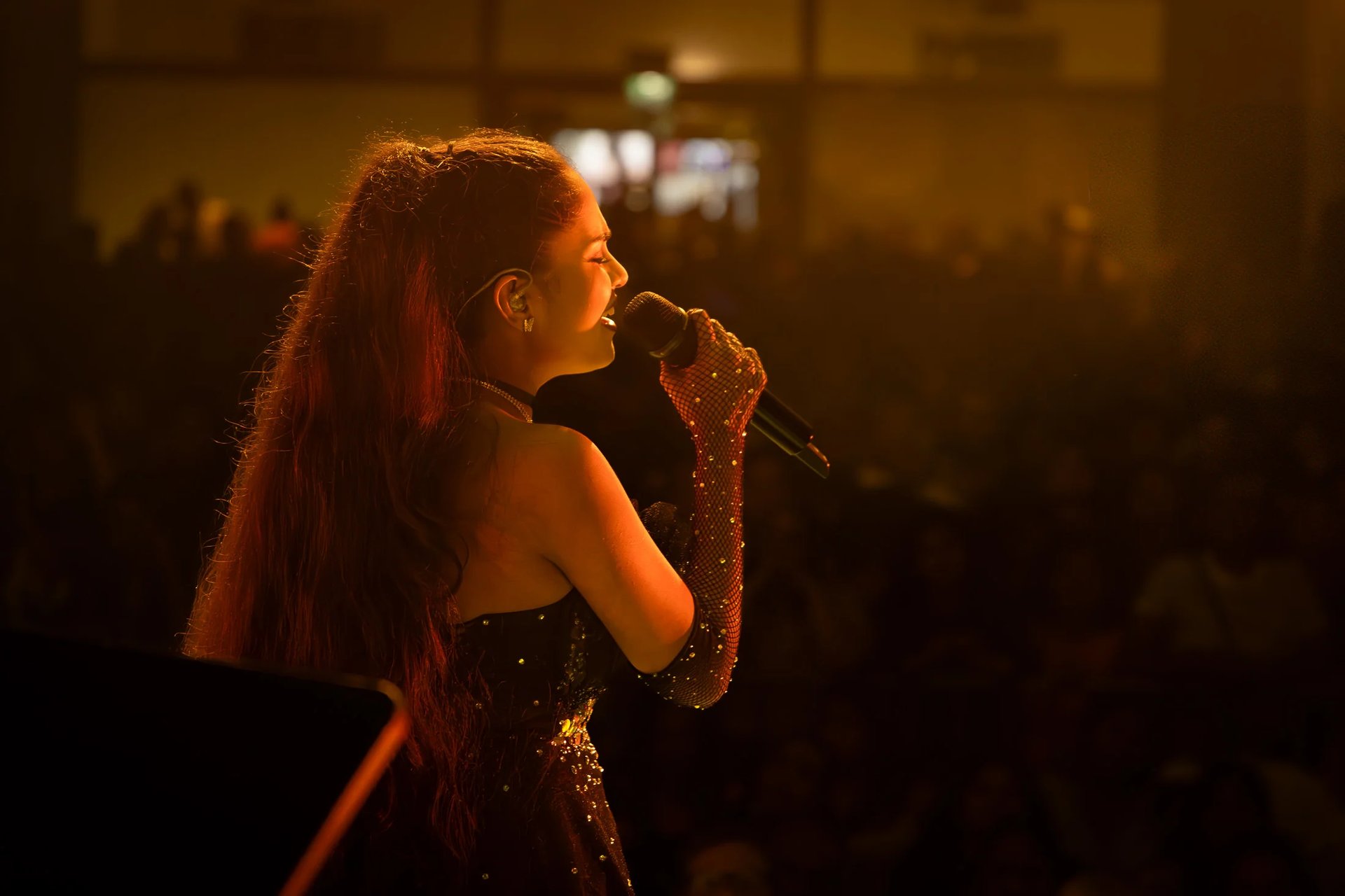 a woman in a black dress singing into a microphone